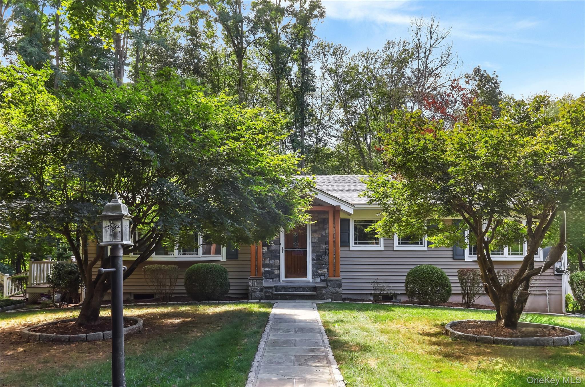 Nestled at the end of a quiet cul-de-sac, this beautifully updated Ranch offers the perfect blend of privacy and charm in a serene wooded setting. The main level features gleaming hardwood floors and updated windows including wood trimmed bay windows throughout. A sun-drenched living room with a striking stone-surround gas fireplace, opens to the dining area with access to a two-tier Trex deck - ideal for entertaining or relaxing in nature. The kitchen is a chef’s dream, boasting granite countertops, tile flooring and backsplash, and stainless steel appliances. Down the hall is the primary bedroom, two additional bedrooms, one with an updated full bath, and a hall bath with a granite vanity and a tiled walk-in shower. Downstairs, the finished lower level offers a versatile family room with walk-out access, a laundry area, and two additional rooms perfect for a home office, gym, or guest space. This home is a true retreat with modern comforts and timeless appeal.