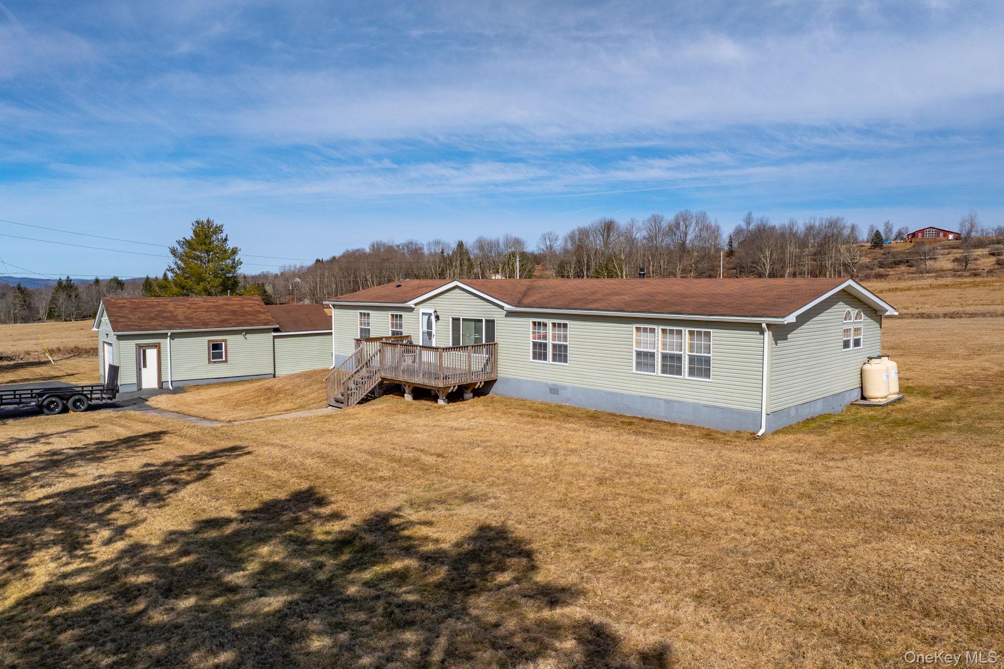Rear view of property featuring a wooden deck, a lawn, an outdoor structure, and crawl space