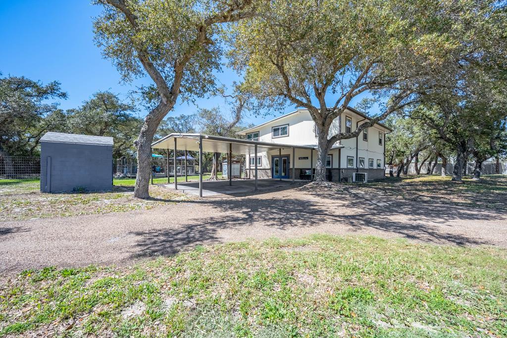 Set on 1.25 tree-filled acres just minutes from Rockport and Aransas Pass, this spacious 4-bedroom, 2-bath property offers privacy, versatility, and income potential. The main home features an open kitchen with abundant cabinetry, extensive counter space, breakfast bar, and dining area that flows into a large living room designed for everyday comfort and entertaining. A flexible upstairs living or game room area includes a wet bar/kitchenette and access to a covered deck, creating the perfect space for gathering, hobbies, or additional living space. Outside, the property truly shines with two dedicated RV parking pads with full hookups—ideal for visiting guests or rental income opportunities. The expansive outdoor deck invites gatherings, stargazing, and relaxing beneath the coastal breeze, while the outdoor shower is perfect for rinsing off after a day at the beach or fishing. Additional highlights include fully paid-off 7,500-watt solar panels, a whole-home filtration system, circular driveway, and covered parking. With plenty of room to add a pool, boat garage, or additional outdoor amenities, this property offers a rare blend of space, functionality, and coastal lifestyle just a short drive from the water. Ask for Features Sheet & Floor Plan!