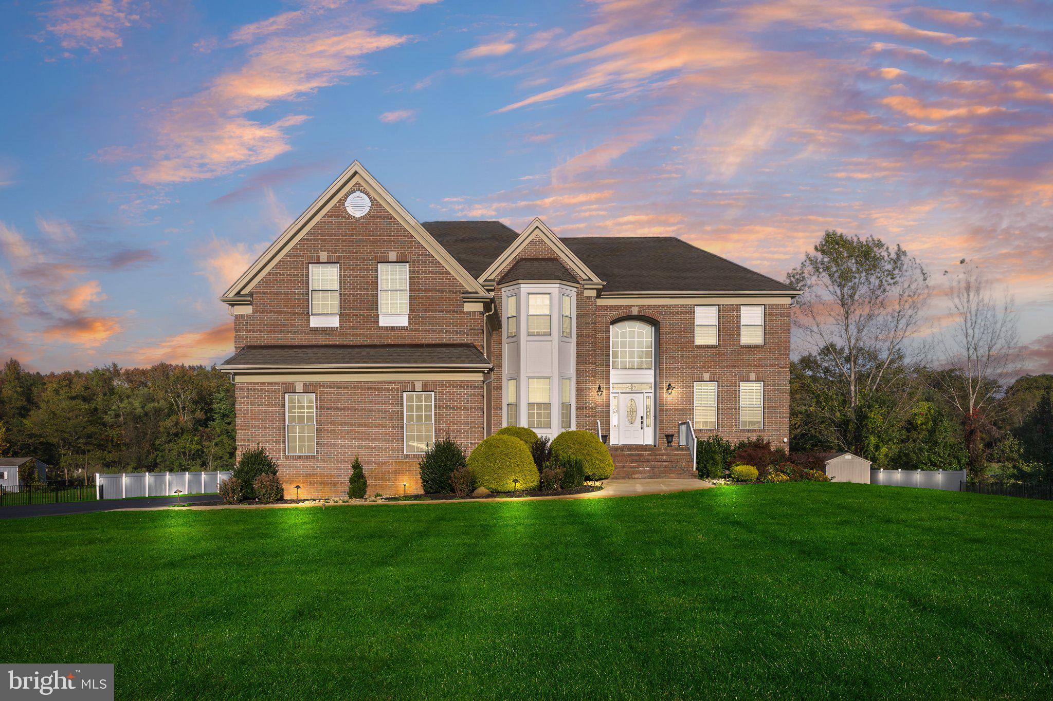 Welcome to 45 Bella Road, a stately brick-front estate where striking architectural details, beautifully designed interiors, and exceptional outdoor living come together on over three acres of picturesque grounds. A sweeping gated driveway, manicured landscaping, and an impressive entrance set the stage for a home that balances sophisticated style with inviting, everyday comfort. A dramatic two-story foyer welcomes you inside, where soaring ceilings, expansive windows, and abundant natural light highlight the home’s architectural character. Crown molding, gorgeous chandeliers, and recessed lighting bring elegance throughout. French doors open to a private first-floor office accented with wainscoting, creating a beautiful setting for working from home. The formal living room flows into the spacious dining room, where chair rail detailing, a tray ceiling, and a statement chandelier provide an elegant backdrop for memorable gatherings. In the family room, oversized arched windows create a stunning focal point, while a fireplace adds warmth to the generously sized space. The expansive kitchen features white cabinetry, granite countertops, newer stainless steel appliances, and ample room to prepare meals and gather. A powder room and laundry room complete the main level, while two stairways enhance the convenience of the thoughtfully designed layout. Upstairs, the impressive primary suite offers a peaceful retreat with a tray ceiling, recessed lighting, a beautiful chandelier, and a separate sitting room. An exceptionally large walk-in closet provides abundant storage, while the newly renovated en-suite bathroom offers a spa-inspired experience with two vanities, a stunning stone-accented walk-in shower with jets, a deep soaking tub, and gorgeous lighting. A second bedroom enjoys its own private full bathroom, while two additional bedrooms share another full bathroom. A bonus loft creates an inviting setting for a reading nook or additional lounge space. The extensively finished lower level offers exceptional versatility, with a spacious additional living area, game room, office, gym, and a separate space for guests to unwind. An enormous walk-in closet with custom shelving and a hidden door adds a distinctive touch, while a newly renovated full bathroom with a beautifully finished walk-in shower brings elevated style to this level. Outdoors, the property becomes a destination of its own. An expansive elevated deck offers dedicated areas for dining, lounging, and entertaining while overlooking the sprawling grounds. Below, a spacious patio with gas fire pits provides an inviting setting for evenings under the stars. A private basketball court, acres of open green space, partial fencing, and extensive exterior lighting create opportunities for recreation, relaxation, and unforgettable gatherings. A three-car garage completes this exceptional property, and furniture can be included for an even more seamless move. From its distinctive architectural details and beautifully renovated bathrooms to its expansive interiors and extraordinary outdoor amenities, 45 Bella Road offers luxury with room to live, gather, and unwind. Schedule your private showing today.