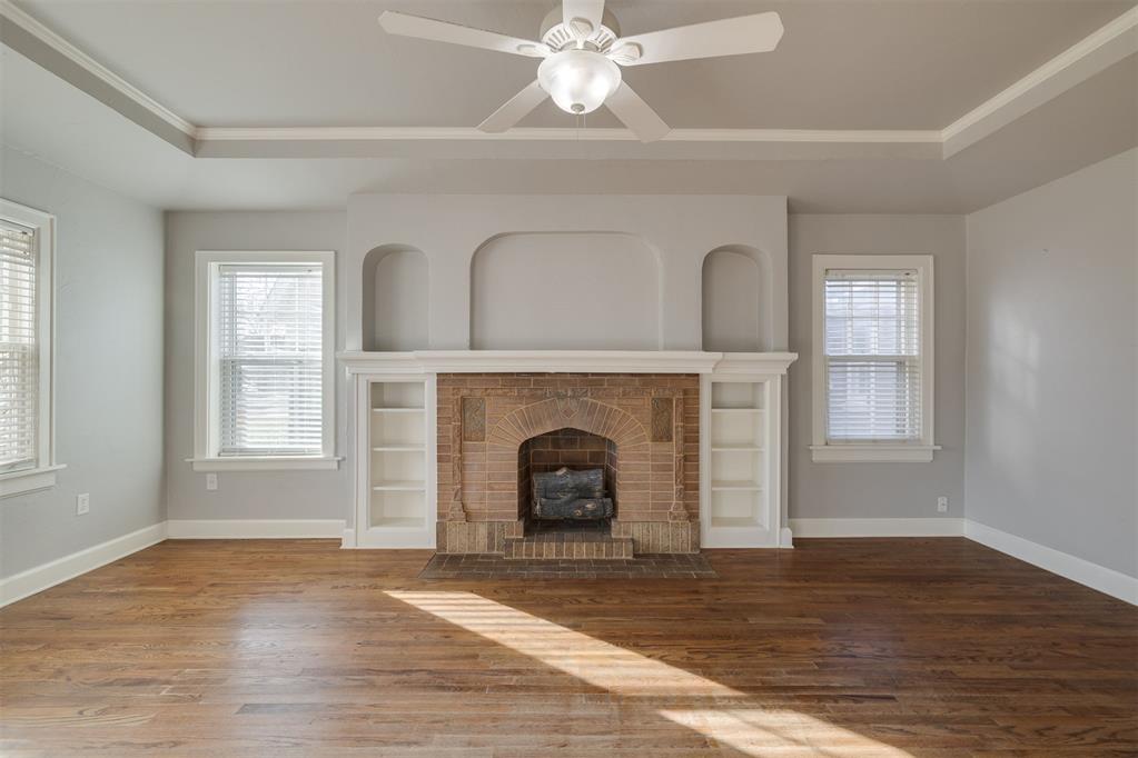 Tucked within the Historic Miller Neighborhood, this classic Tudor-style home blends timeless design with everyday comfort. The blonde brick exterior showcases the home’s character and curb appeal, setting the stage for what’s inside. Step into the inviting living room, where built-in shelving, graceful decorative arches, and a tray ceiling create an airy, elegant atmosphere. The brick fireplace features lovely decorative details, adding a charming focal point that brings the room together. Original hardwood floors flow throughout the home, lending warmth and continuity to each space. The formal dining room highlights another beautiful tray ceiling, perfect for hosting gatherings under soft light. A second dining area offers a casual space for everyday meals, featuring built-in cabinetry that combines functionality with period charm. The kitchen includes tile flooring and updated stainless steel appliances, blending practical convenience with a classic aesthetic. In the bathroom, original-style basket-weave tile offers a touch of vintage appeal alongside a large single vanity with extra storage. A full-size bathtub and shower combo completes this thoughtfully designed space. Recent functional updates include the roof and electrical service panel. Every detail of this home reflects its historic character — from the architectural lines to the preserved finishes — while providing the modern features that make daily living seamless. It’s a polished example of how history and comfort can coexist beautifully.