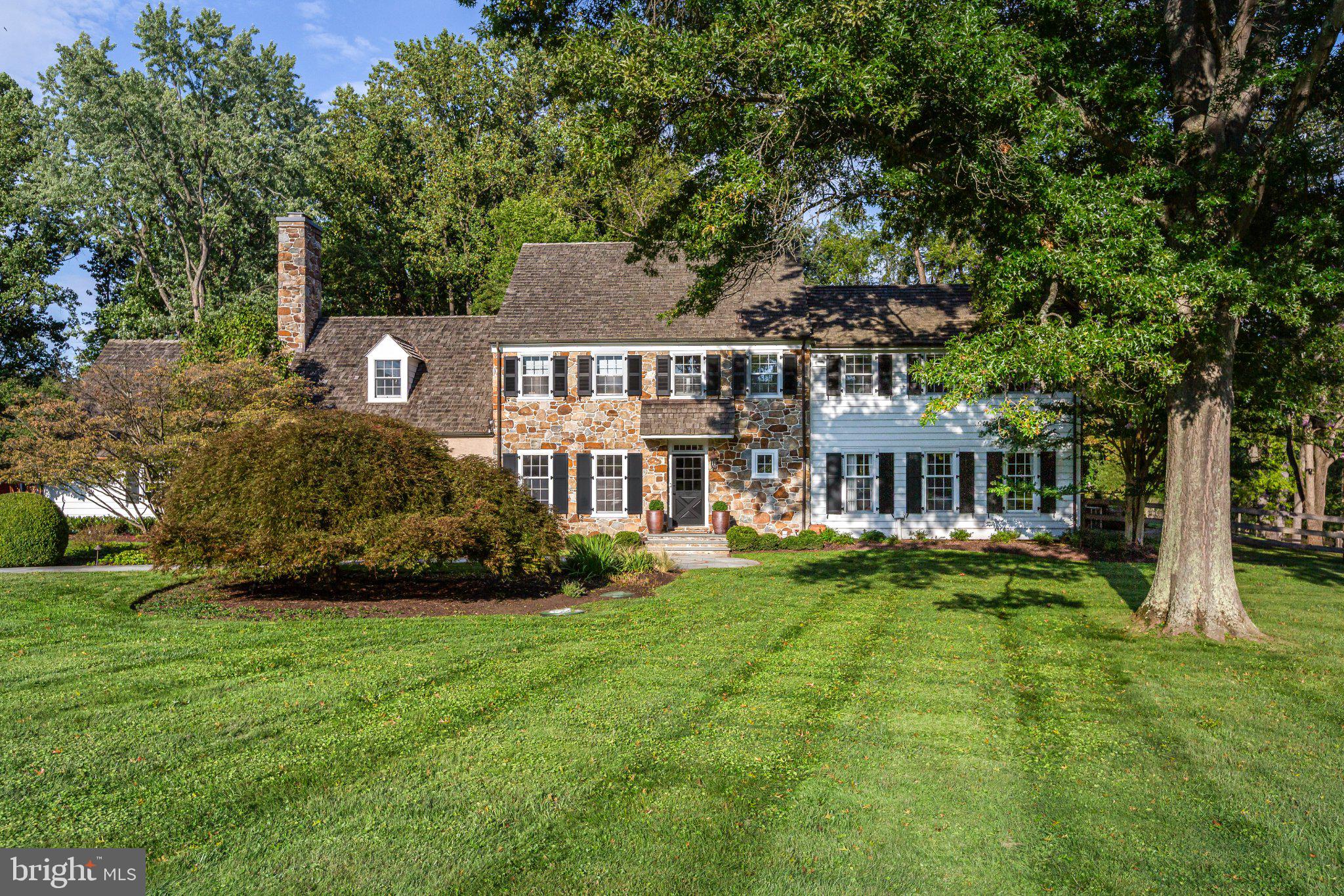 A QUINTESSENTIAL WILLISTOWN HOME Set in a private, peaceful setting framed by spectacular trees and professional landscaping, this authentic stone Colonial exudes understated elegance from the moment you approach along the long driveway. Adorned with attractive wood shutters, copper gutters, and a lovely flagstone walkway, the home immediately conveys a sense of calm and timeless beauty. TIMELESS CURB APPEAL Inside, the sun-filled main level features rich wood floors, substantial millwork, custom built-ins, and two fireplaces. The inviting living room centers around a fireplace framed by original Moravian Tile Works tiles surrounding a brick hearth, with large front-facing windows and French doors that open to an extraordinary screened-in porch featuring a coffered ceiling, attractive lighting, and automatic retractable screens. MAIN LEVEL The main level continues with an elegant formal dining room highlighted by crown molding and large windows. A thoughtfully renovated kitchen features a beamed ceiling, custom inset cabinetry, quartz countertops, classic subway tile backsplash, and a center island with casual seating alongside a dedicated breakfast area. It comes fully equipped with stainless chef-grade appliances, including a Thermador refrigerator, wine fridge, speed oven and gas oven range. The comfortable family room boasts a second fireplace flanked by built-ins and wood storage, as well as a large bay window with a built-in window seat. Completing the main floor is a well-appointed powder room and a state-of-the-art mudroom that doubles as a laundry and pantry space—complete with ample custom cabinetry, generous counter space, and a sink—making everyday living exceptionally functional and organized, while also serving as a convenient catering kitchen when entertaining larger gatherings. There is a convenient back staircase off of the family room. ROOM FOR EVERYONE A gracious front staircase and a secondary rear staircase provide convenient access to the second floor, where sun-filled rooms and picturesque views unfold from nearly every window. The spacious primary suite offers ample room for a dedicated seating area and features a  luxury custom closet alongside a renovated primary bath appointed with double vanities, a walk-in shower, Carrara marble, and elegant finishes. Two additional bedrooms include custom built-ins, generous closet space, and share an updated hall bathroom, while a charming fourth bedroom features its own updated en-suite bathroom. FLEXIBILITY & OPPORTUNITY Continuing upward, custom-milled stairs and railings lead to an unexpected fifth room with uplighted beamed ceilings and abundant natural light– ideal for use as a home office, hobby room, creative studio, or teen suite. Adding to the character of the grounds is a picturesque barn offering incredible potential to be reimagined as a party barn, pool house, yoga studio, or customized flex space. SOUGHT-AFTER SETTING Outside, the exceptional setting, heated sparkling pool, and open outdoor spaces create a seamless connection to the natural beauty of Willistown Township. The home is perfectly positioned to enjoy everything the area has to offer, including Radnor Hunt, Okehocking Preserve, top-tier golf, nearby parks, the highly regarded Great Valley School District, and several renowned private schools. UNBEATABLE ACCESSIBILITY Residents will appreciate convenient access to the charming borough of Malvern, with its beloved dining and shopping destinations including The Buttery, Kimberton Whole Foods, Anthony’s, Restaurant Alba, and the historic General Warren Inne. Equally close are the exceptional restaurants, boutiques, and amenities of Wayne, offering even more opportunities for dining, shopping, and entertainment. The nearby Paoli train station provides direct service to both Philadelphia and New York City.