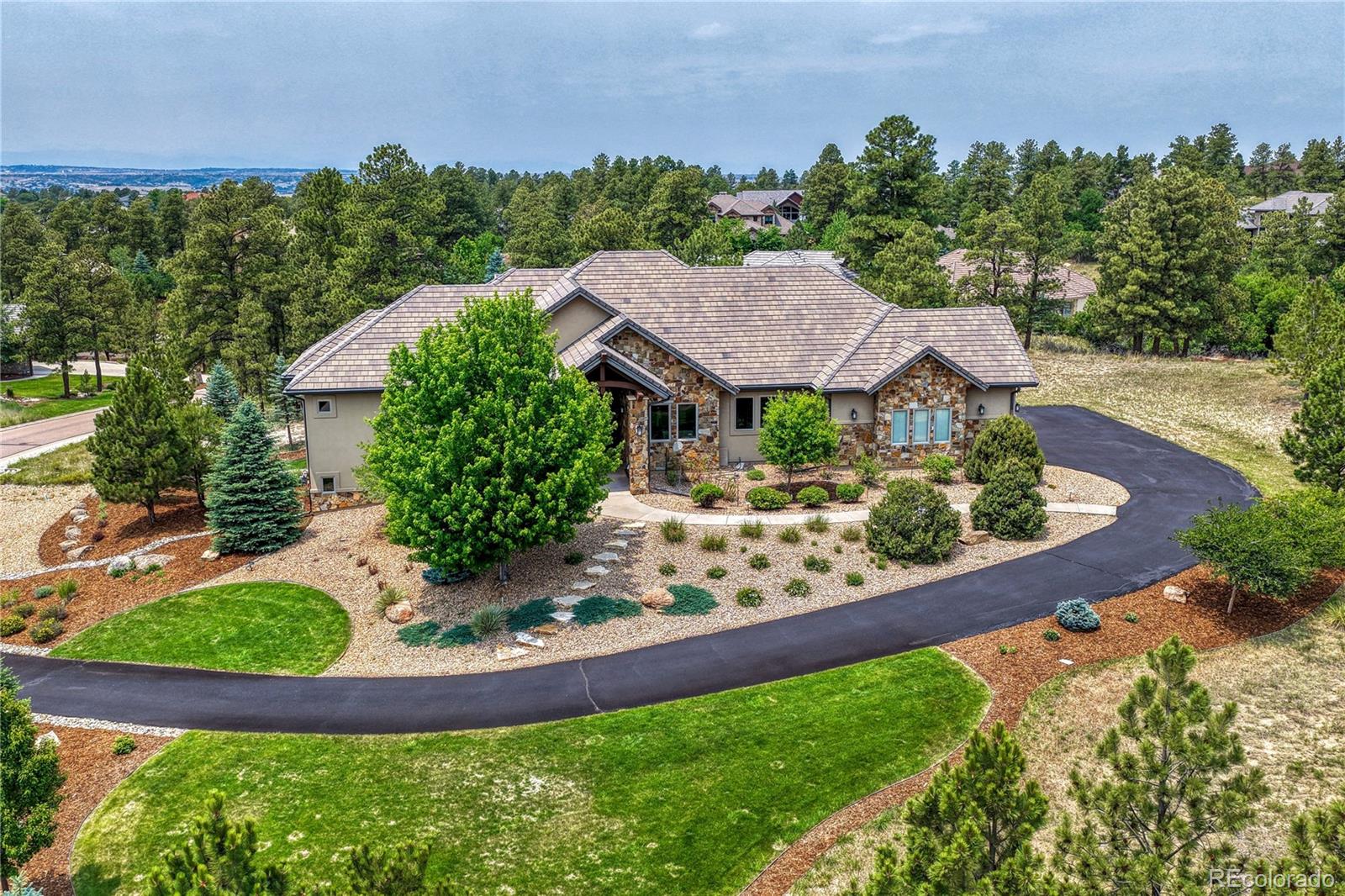 Nestled within The Retreat at The Timbers this exceptional mountain contemporary ranch blends timeless design and outstanding craftsmanship. Positioned atop a beautifully landscaped 0.86-acre cul-de-sac street lot, the home was thoughtfully sited to maximize seclusion while embracing the surrounding natural beauty.Designed for both everyday living and effortless entertaining, the main level showcases soaring ceilings, character-grade Hickory hardwood flooring, custom cabinetry, premium stone surfaces, and exceptional millwork throughout. Expansive windows fill the home with natural light, while the open great room flows seamlessly to a private rear deck and an extraordinary chef's kitchen featuring dual islands, a commercial-grade BlueStar range with griddle and double ovens, built-in refrigerator, custom hood, butler's pantry, beverage cooler, walk-in pantry, and abundant workspace. The spacious main-level primary suite offers a luxurious retreat with a spa-inspired bath featuring an oversized walk-in shower, soaking tub, dual vanities, and an expansive walk-in closet. The main floor also includes a breakfast nook, formal dining room, and private office. The walkout lower level is designed for entertaining with three spacious guest suites, each with a private ensuite bath, a full bar, large family room, dedicated media room with elevated bar seating, game and poker room, and additional laundry hookups. A highly desirable four-car garage provides generous space for vehicles, storage, and hobbies, while the durable concrete tile roof offers outstanding hail and fire resistance and the potential for lower insurance costs. The Retreat at The Timbers is a distinguished collection of custom homes along a private cul-de-sac, where many of the area's premier builders showcased their finest craftsmanship, innovative floor plans, and architectural design. The result is one of Parker's most sought-after luxury communities, known for its larger homes & exceptional quality.