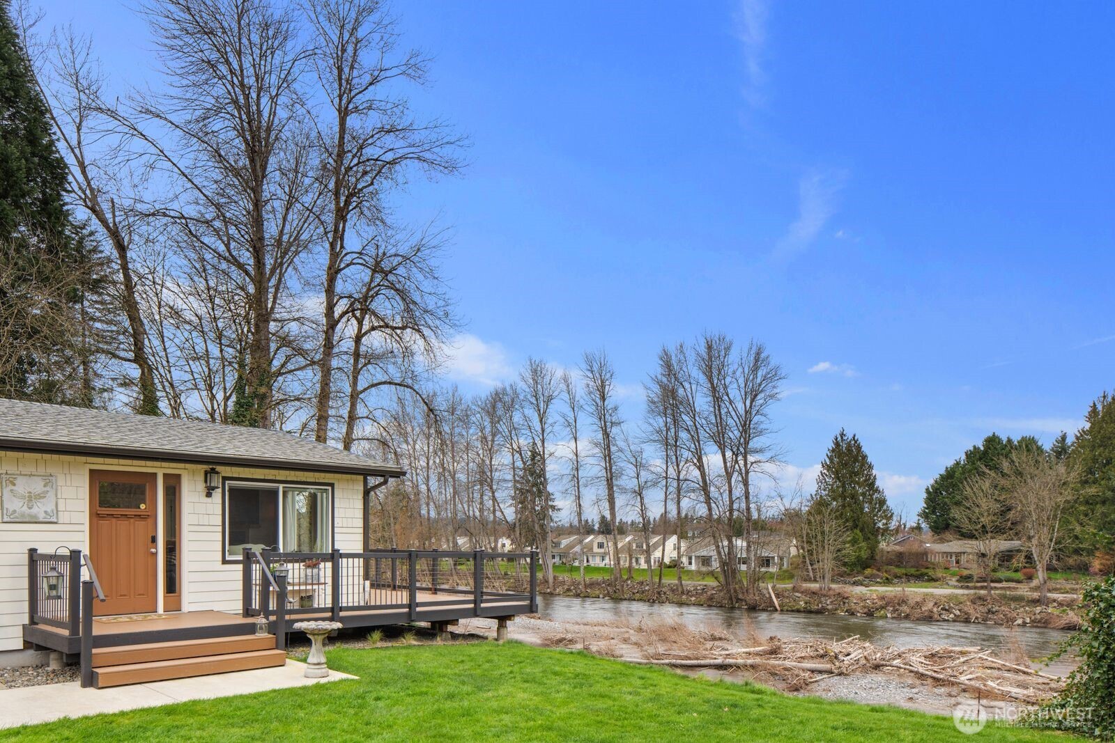 One of the last riverfront properties grandfathered in without restrictive waterfront setbacks. Perched on a high bank above the river, this home sits safely outside the flood zone while offering breathtaking views and direct access to nature. The river is full of salmon, creating a truly special Pacific Northwest setting, all while being just minutes from the charm, restaurants, and events of downtown Puyallup.  This beautiful custom home features a bright primary suite with a spa-like ensuite bathroom designed for comfort and relaxation. Large windows throughout the home frame stunning river views from nearly every room, filling the interior with natural light.  The spacious kitchen is designed for both everyday living and gourmet cooking, featuring abundant cabinetry, a large island for gathering and prep space, and a gas stove perfect for home chefs.   The property also includes versatile outbuildings, ideal for a home office, art studio, or creative workspace. Practical upgrades include generator wiring, a gas fireplace, and a heat pump for year-round efficiency and comfort.  Enjoy a riverfront sanctuary with panoramic 180-degree views from the expansive open living room. With the home perched along the high-bank edge, you’ll experience the rare feeling of being just steps from the water while maintaining privacy and elevation.  Additional features include a gated private driveway with ample off-street parking and an oversized detached garage with workshop space.