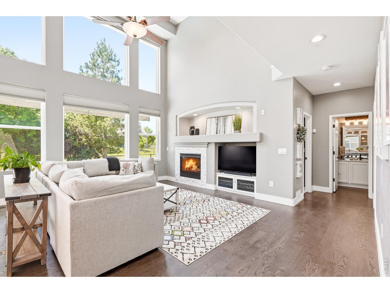 Fresh, bright, and thoughtfully designed, this 6 bedroom, 4 bathroom Longmont home offers 3,880 square feet of flexible living space, a beautiful neutral color palette, and a backyard retreat built for Colorado living. Hardwood floors lead from the two-story foyer into the main living area, where soaring windows fill the space with natural light. The living room features a built-in entertainment center with shelving, accent lighting, and a custom tile gas fireplace. The kitchen connects easily to the living room and breakfast nook, with updated counters, fresh paint, subway tile backsplash, stainless steel appliances, modern accent lighting, ample workspace, and a large window over the sink. Sliding doors open to an extended deck and a park-like backyard.The main level includes a dedicated office with double doors, built-in desk, and cabinetry, plus a bright main floor bedroom with access to a full bathroom. Upstairs, the primary suite offers vaulted ceilings, generous natural light, double-door entry, a beautifully updated bathroom with dual vanity, soaking tub, glass and tile shower, private water closet, and an impressive walk-in closet with built-in organization and a large window. Three additional upstairs bedrooms share a full bathroom with double vanity.The finished basement lives like an extension of the home with a living area, kitchenette, dining space, additional bedroom, office space, windows for natural light, and a gas fireplace. Outside, the custom 11,000-gallon saltwater pool, water feature, patio, shed, and basketball court create a rare backyard setup. Situated on a quarter acre and backing to open space, this Elms at Meadow Vale property offers space, function, and a true retreat feel. Note: The monthly neighborhood HOA fee covers exterior water for this property's yard and for all of the homes in The Elms at Meadow Vale.