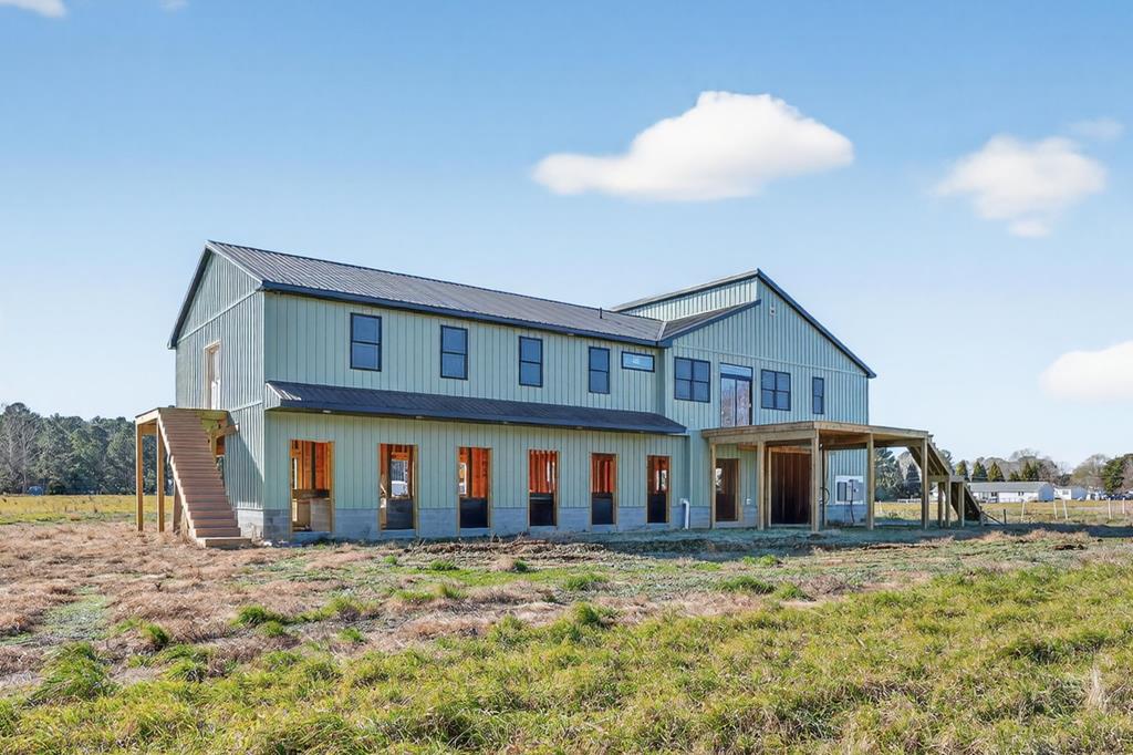 Rare opportunity to create an equestrian/farm retreat on over 36 acres in Wallops Island. This under-construction barndominium features 3,000+ sq ft of stable space with 18 stalls and a first-floor half bath, ideal for daily barn use and livestock care. The upper level offers 2,400+ sq ft with 3 bedrooms and 2 full baths. A spacious mudroom-style foyer opens to an open kitchen, dining, and living area with access to a large deck overlooking pastureland bordered by a tree line. Two guest bedrooms share a full bath and deck access, while the primary suite includes a walk-in closet & private bath. Luxury vinyl plank flooring and recessed lighting throughout. Buyer may select finishes or purchase as-is. Convenient to Wallops Flight Facility, Assateague Island beaches, and Chincoteague Island!