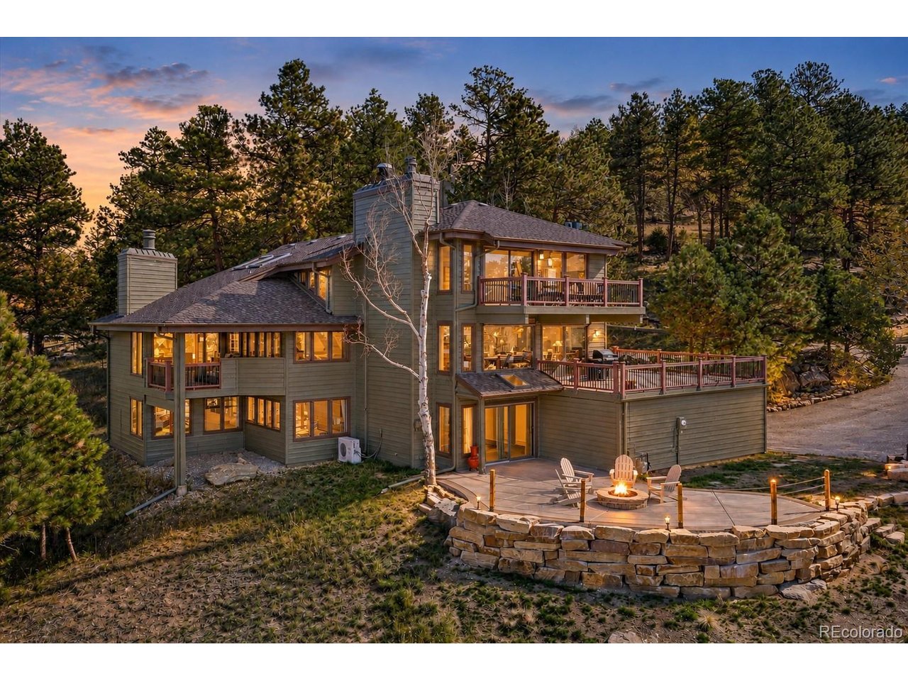 Panoramic Mountain Views. Snowcapped Mount Blue Sky. Exceptional Indoor-Outdoor Living. Imagine starting your morning with coffee on the covered deck, watching the light move across the mountains & ending the day with a glass of wine by the fire on the patio as the sun slips behind the ridgeline. With panoramic mountain views, inviting gathering spaces & multiple outdoor living areas, this Genesee home makes the most of its remarkable Colorado setting. Here, the views become part of daily life.Warm architectural details and thoughtfully designed living spaces create a welcoming atmosphere throughout. The living room features vaulted beamed ceilings, moss rock fireplace & access to the covered deck. At the heart of the home, the kitchen offers generous cabinetry, expansive counter space, gas range, breakfast bar seating & casual dining nook. An adjoining family room is framed by a wall of windows showcasing the mountain views, with a fireplace & direct access to the expansive deck. The dining room adds another inviting space for entertaining, complete with a serving bar featuring concrete countertops, a beverage refrigerator, & built-in kegerator. Upstairs, the primary suite offers a peaceful retreat with sweeping views through a wall of windows, cozy fireplace & private balcony overlooking the mountains. The five-piece bath features stone accents & a spacious walk-in shower, while a generous walk-in closet provides ample storage. A versatile loft offers an ideal home office space. The walkout lower level is equally inviting, featuring a family room opening to the patio and built-in fire pit, a private guest suite with an ensuite bath, two additional bedrooms & three-quarter bath with a steam shower. Beyond the home, enjoy the Genesee lifestyle with 1,200 acres of open space, 12 miles of scenic trails, two swimming pools, tennis and pickleball courts, a fitness center & community events, all just 30 minutes from downtown Denver.