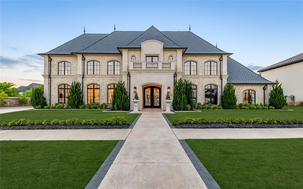 Set within the prestigious guard-gated Homestead enclave of Newman Village—one of Frisco’s most exclusive neighborhoods—this sculptured stone masterpiece sits on a prime corner lot with abundant natural light and sunlight. The modern French chateau, blends timeless architecture with elevated finishes for grand elegance and effortless living.The striking stone exterior welcomes you through wrought-iron doors into a luminous two-story foyer with sculptural staircase, oak floors, and exquisite millwork. The sun-splashed great room features twin brass ring chandeliers, Turkish quarry fireplaces, and a dramatic wall of glass framing courtyard views.The stunning kitchen impresses with a Sub-Zero fridge, Wolf dual oven, large island, and pantry. A temperature-controlled, walk-in, wine room sits right off the kitchen and dining area. Off the entry is a dream home office with navy tones, floor-to-ceiling built-ins, and a wet bar. Upstairs, a refined lounge with full wet bar anchors a plush media room and cinematic theater.The serene primary suite downstairs includes his-and-hers closets and outdoor access, highlighted by a boutique-style dressing room with glass displays, shoe galleries, extensive drawers, and a marble island under a sparkling chandelier. Stone pavers lead to a pristine pool and raised glass-tile spa, flanked by covered loggias with outdoor fireplace and TV—perfect for year-round entertaining. Multiple sunning zones and seamless indoor-outdoor flow create a private resort feel, enhanced by a heated outdoor eating area and full outdoor kitchen.A tornado shelter, whole-home Control4 automation, water filtration system, Generac generator, epoxy garage floors, landscape lighting, and security cameras add convenience and security. Located in Frisco ISD (Newman Elementary), this immaculate 8,150 sq ft estate offers the ultimate in luxury and resort-style living.