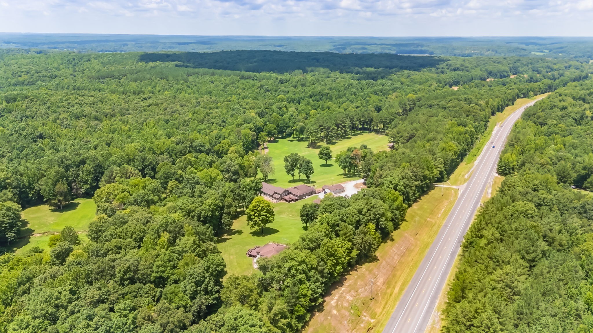 Just over an hour west of Nashville with convenient access to I-40, Legacy Acres offers 124± private acres where recreation, relaxation, and country living come together. Whether you're looking for a full-time residence, family retreat, hunting property, equestrian farm, or weekend escape, this remarkable property offers endless possibilities. The centerpiece of this private gated retreat is a charming two-bedroom home with expansive windows overlooking a peaceful valley, a year-round creek, and abundant wildlife. An indoor swimming pool provides year-round enjoyment, while a separate mother-in-law cottage, standalone guest suite, and caretaker's home offer exceptional flexibility for guests, extended family, rental income, or on-site property management. Additional improvements include a two-car garage, carport, greenhouse, equipment shed, and tractor barn. The land features a beautiful mix of open pasture and mature timber, making it ideal for horses, livestock, hunting, hiking, ATV riding, or simply enjoying nature. A stocked half-acre catfish pond and the scenic creek add to the property's beauty and recreational appeal. Wildlife is plentiful, with healthy populations of deer, turkey, and small game, and there is ample space for food plots, gardens, horseback riding, target shooting, or archery. Despite its private setting, the property offers fiber high-speed internet, making remote work easy while enjoying the peace of country living. It's also conveniently located near the Tennessee River, Kentucky Lake, the Buffalo River, and the Duck River for boating, fishing, kayaking, and additional outdoor recreation. With no restrictions, Legacy Acres offers the freedom to create the lifestyle you've always envisioned. Opportunities to own a property with this combination of privacy, improvements, natural beauty, recreation, and accessibility are increasingly rare.