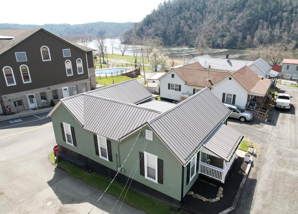 Step into this completely remodeled 1900 home in the heart of Fries, located less than 200 yards from the scenic New River and the renowned New River Trail, and directly across the street from the Fries Theatre and Recreation Center. This charming 2-bedroom, 1.5-bath furnished home offers approximately 1,248 square feet of living space and was thoughtfully remodeled in 2022, blending historic character with modern updates. Inside, you'll find original wood floors throughout, along with updated plumbing, electrical, HVAC, a durable metal roof, and fresh paint. The spacious kitchen features an island with a built-in stove, while a stunning custom window immediately draws your attention with beautiful river views. Replacement vinyl windows and Levolor blinds are installed throughout the home. Both bedrooms are generously sized and showcase original fireplaces, with the primary bedroom offering a private half bath. The large living room also features a fireplace, creating a warm and inviting space. Step outside to enjoy outdoor living on the covered front porch or the expansive back porch—perfect for grilling, relaxing, or taking in the fresh mountain air and river scenery. Conveniently located less than 100 yards from local favorites including Fries Dam Steakhouse, Windy River Cafe, The Depot, the local farmers market, and library, this home offers exceptional walkability and easy access to dining, shopping, and recreation. Enjoy biking, hiking, and horseback riding along the New River Trail, or take advantage of the New River for fishing, swimming, tubing, or simply relaxing by the water. Fries also hosts a variety of community events throughout the year, from riverside car shows to bluegrass music at the theatre. Whether you're looking for a primary residence, mountain getaway, or an investment opportunity such as an Airbnb, this unique property offers it all. Don't miss your chance to own a piece of history just steps from the iconic New River!