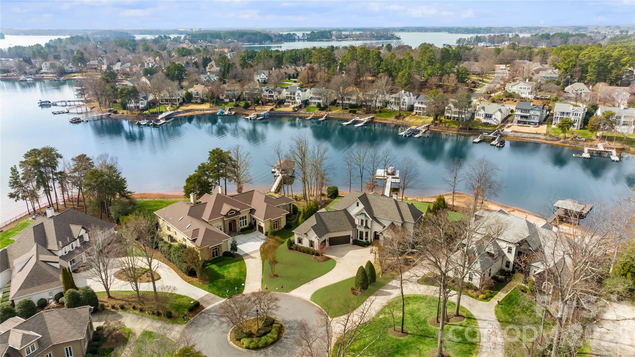 Waterfront luxury in this exceptional all-brick estate nestled within the prestigious Peninsula community. Showcasing quiet cove views of Lake Norman, this updated residence seamlessly blends elegance with modern luxury.  Outdoor living is unrivaled, featuring covered wraparound loggias, an outdoor kitchen, a stone fireplace, heated pool and spa, pool bath, outdoor shower, private dock, and a sprawling fenced lakeside lawn ideal for entertaining and recreation.  Thoughtfully designed main level offers an expansive open floor plan highlighted by walls of sliding glass doors that capture stunning water views and create effortless indoor-outdoor living. At the heart of the home is a fully renovated chef's kitchen featuring quartzite island, custom cabinetry, dual dishwashers, premium appliances, and a beautifully appointed scullery for additional preparation and storage. The luxurious primary suite serves as a private retreat with a spa-inspired bath, custom closet, personal laundry area. Additional main-level spaces include a welcoming great room with fireplace, formal dining room with coffered ceiling, keeping room and breakfast nook with banquette.  Upstairs, three generously sized bedrooms each enjoy beautifully updated en-suite baths with designer wall coverings. A spacious bonus room offers flexibility as a fifth bedroom, media room, or playroom. A dedicated office  room and full-size laundry room complete the upper level.Additional highlights include a 3-car epoxy garage enhanced by a professional-grade automotive storage lift, allowing expanded vehicle capacity for car enthusiasts and collectors.  Located just a short stroll from The Peninsula Golf Club and minutes from premier dining, shopping, and conveniences, this remarkable waterfront residence offers the very best of Lake Norman luxury living.