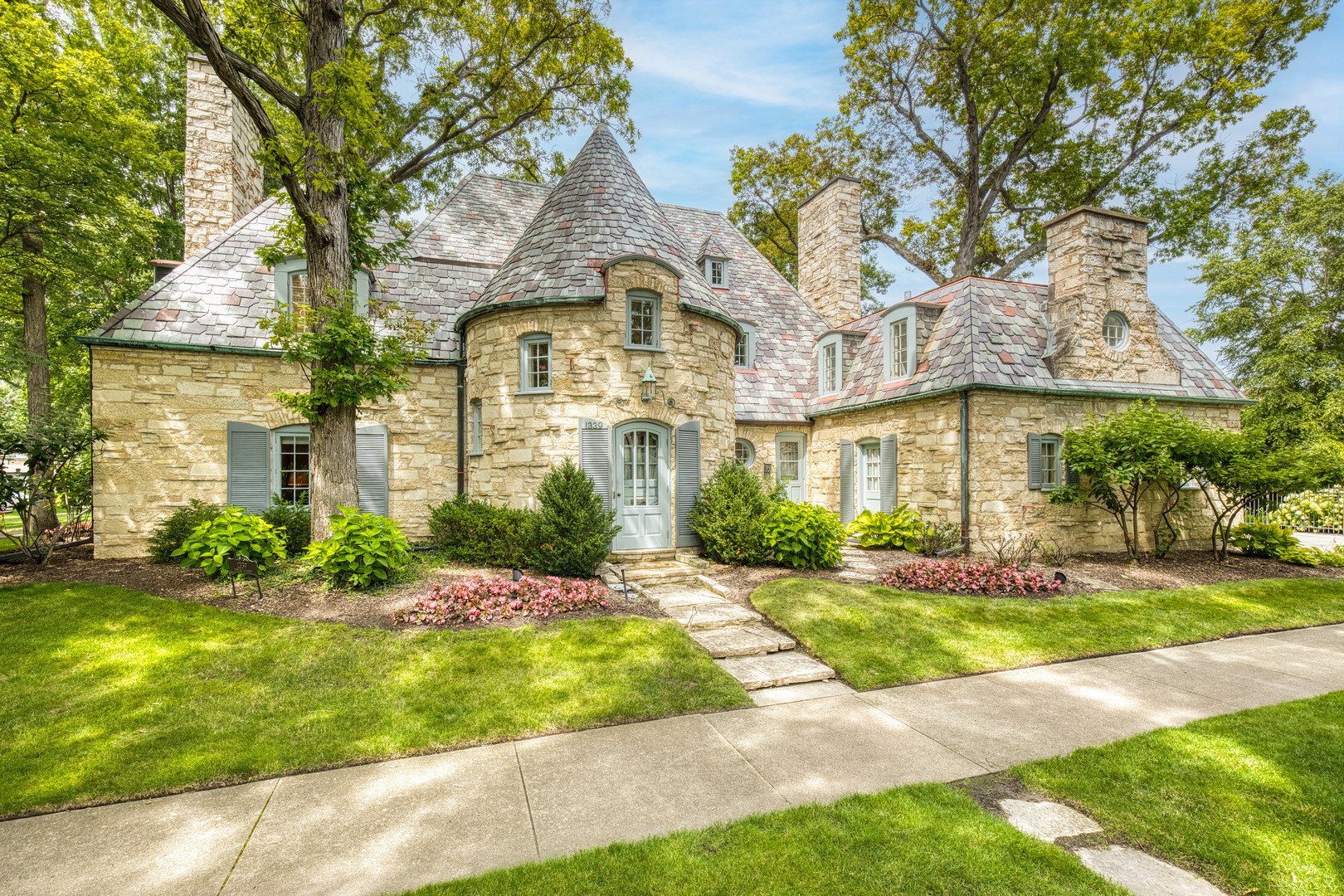 A rare opportunity to own a French Eclectic residence designed by noted architect Jerome R. Cerny. Cherished by only two owners. The dramatic foyer sets the tone. A striking wrought-iron staircase, curved walls, and refinished hardwood floors welcome you into the home. The living room features a gas fireplace, custom built-in bookcases, and elegant crown molding, while the formal dining room is highlighted by a beautiful bay window, creating the perfect setting for family gatherings. The sun-filled kitchen is both functional and inviting, featuring a bay window overlooking the backyard, quartz countertops, abundant cabinetry, generous prep space, and a butler's pantry. A large second-floor landing opens to four bedrooms, each offering generous closet space. The cozy primary suite offers a gas fireplace and a renovated en-suite bath. The fourth bedroom includes its own renovated full bath, while two additional bedrooms share a connecting full bath. The lower level features a spacious family room with a third fireplace and custom built-in shelving and media area. The oversized utility room offers laundry along with flexible space for a home office, exercise room, storage, or additional living needs with room to add a fourth bath. The two-car attached garage offers convenience and additional storage. Enjoy a beautifully landscaped backyard with a large stone patio and plenty space for entertaining. Located just two blocks from top-rated Willard Elementary School and Constitution Park, with nearby restaurants, shopping & more.