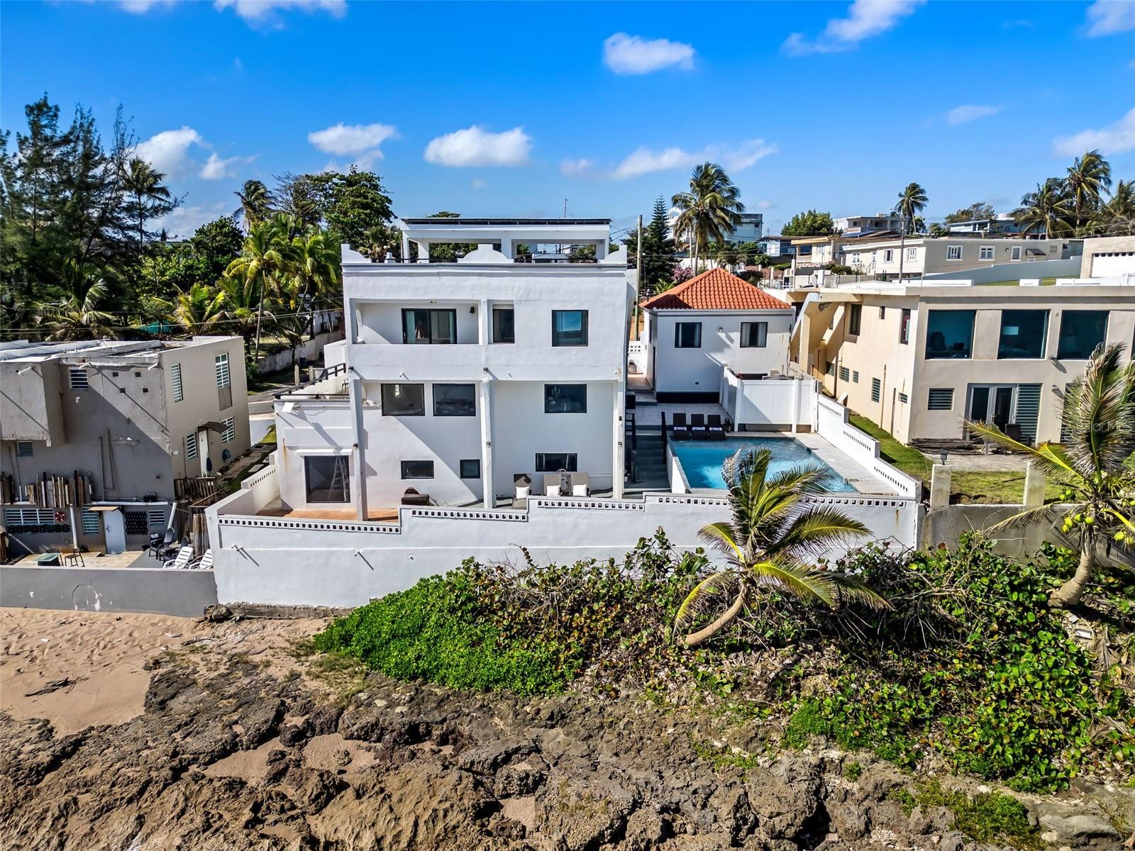 Rare oceanfront investment in Dorado: a turnkey, 5,200 sq.ft., multifamily estate on a 412 sqm lot. Located next to a premier surfing beach with unobstructed ocean views, this three-unit property is optimized for high-yield short-term rentals or a private family compound.Property Highlights:Main Residence: 4 BR / 3 BA with a panoramic rooftop terrace.Studio Unit: Private 1 BR / 1 BA with full kitchen.Apartment: 2 BR / 2 BA for additional rental income.Amenities: Heated oceanfront saltwater pool, covered roof top terrace, solar panels with battery backup, garage, STR permitted and a 650-gallon water cistern.Offered fully furnished and resiliently equipped, this versatile asset is ready for immediate operation in Puerto Rico’s competitive vacation market. No HOA