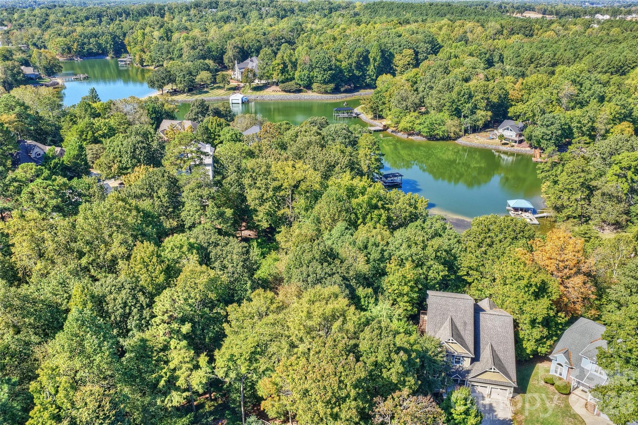 Enjoy lakefront living on Lake Wylie in this beautifully appointed waterfront home, situated on over half an acre along Windjammer Cove in Tega Cay. Located on a private cul-de-sac lot, the property features a covered boat slip with lift, fenced backyard and multiple outdoor living spaces, including a deck, patio and a newly added screened porch. The thoughtfully designed floor plan offers five bedrooms, a spacious bonus room, private office and numerous flex spaces to accommodate a variety of needs. The main-level primary suite features lake views, while the open kitchen offers granite countertops, an island and stainless steel appliances. Upstairs, three additional bedrooms and a spacious bonus room provide ample flexibility. The finished walk-out basement adds even more living space, including a fifth bedroom and full bath, recreation room, wet bar and additional flex space ideal for a fitness room, playroom or study. Additional features include an oversized two-car garage, fresh interior paint and new carpet. With no HOA and direct access to Lake Wylie, this home offers a combination of space, privacy and versatile living in a sought-after waterfront setting.  Convenient to Tega Cay's many amenities, including the golf course, tennis courts, walking trails, parks, marina and Beach & Swim Center. Nearby shopping and dining provide additional convenience, while the location offers easy access to Fort Mill and Charlotte.