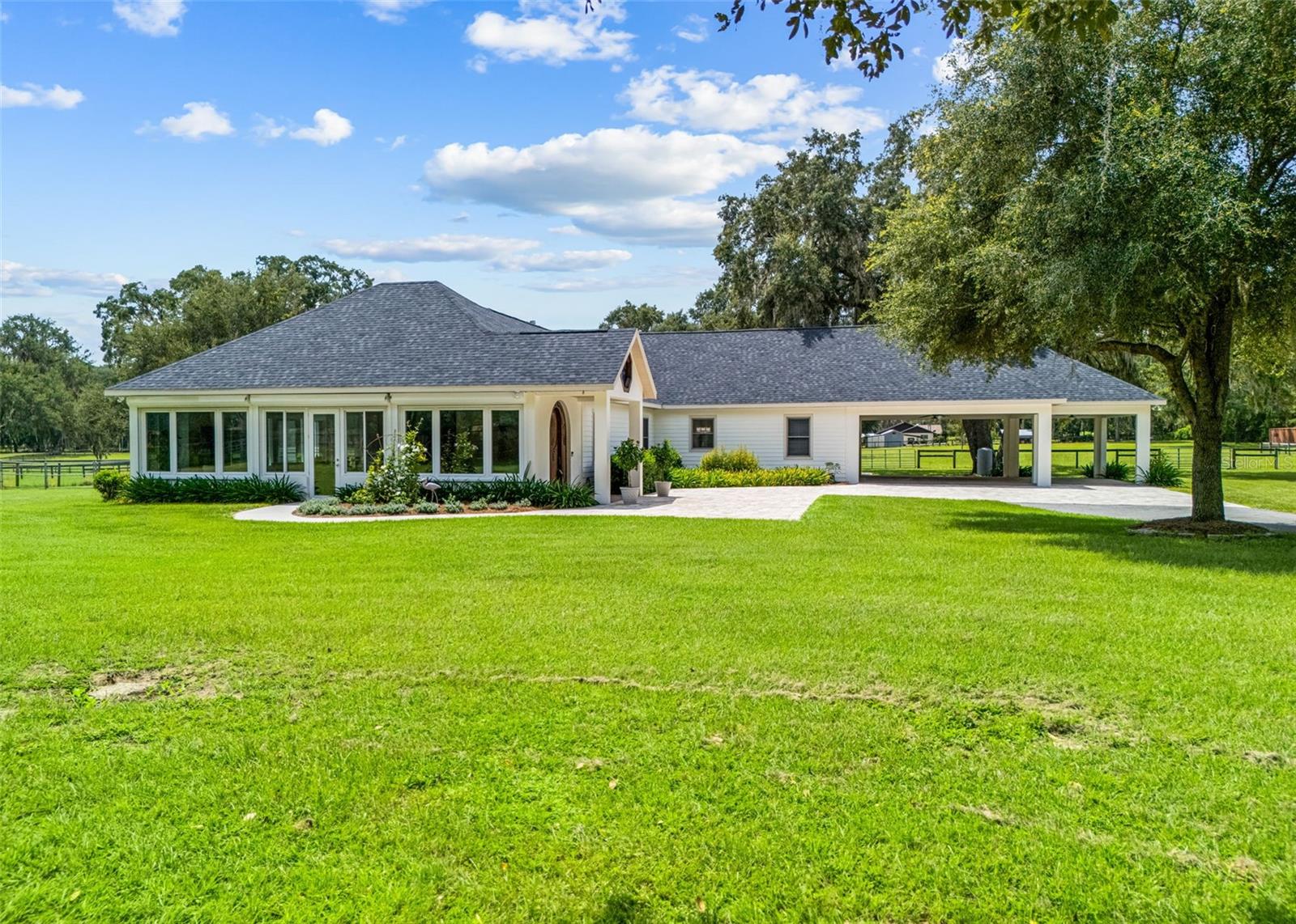 Welcome to a truly exceptional equestrian estate where quality craftsmanship, thoughtful design, and the beauty of nature come together. Tucked away in a peaceful, private setting, this property features a custom built main residence, a beautifully appointed barndominium, and everything needed to enjoy the best of life in the heart of Florida’s horse country.Step through the solid oak front door into a home designed to embrace its surroundings, where expansive windows frame picturesque views of lush pastures and majestic oak trees. The open concept living, dining, and kitchen area creates a warm, inviting atmosphere with vaulted ceilings, custom 42-inch wood cabinetry, granite countertops, and quality finishes throughout.The spacious primary suite is a true retreat, complete with dual vanities, a zero entry walk in shower, a Bain jetted soaking tub, and a generous walk in closet. A separate guest suite offers exceptional flexibility with its own private entrance, office space, screened porch, and butler’s pantry ideal for extended family, guests, or multigenerational living.The thoughtfully designed barndominium offers an additional two bedrooms and two full bathrooms, a full kitchen, dining area, laundry, and comfortable living space. Attached is a dedicated barn office and tack room, making daily farm operations both convenient and efficient.Equestrians will appreciate the five stall center aisle barn with a wash rack and direct access to four beautifully maintained pastures, all established with excellent grass and shaded by mature oaks. A separate small animal barn provides the perfect space for minis, donkeys, or other farm companions. Meticulously maintained and truly move in ready, this property is packed with upgrades including a whole home Generac generator, automatic storm shutters, and pre wiring for an outdoor kitchen. Best of all, enjoy riding access to the Greenway Trail and the Florida Horse Park, while remaining just minutes from shopping, feed stores, healthcare, and all that Ocala has to offer.