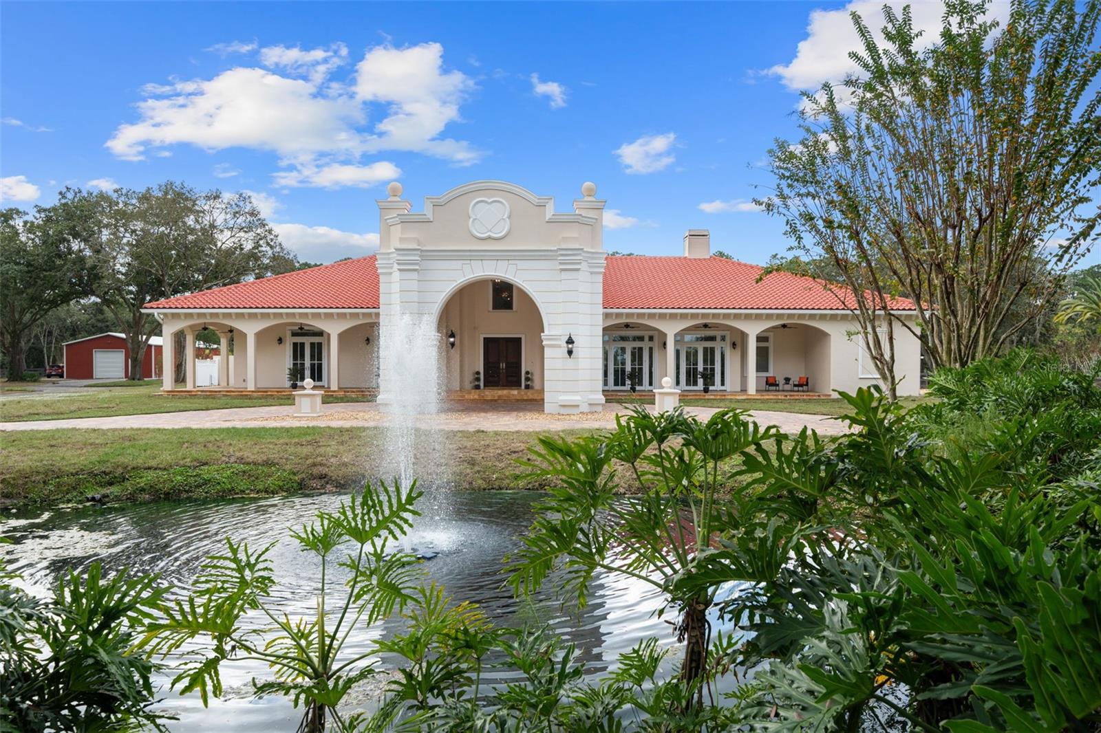 One or more photo(s) has been virtually staged. Welcome to the Sanctuary, where sophistication meets seclusion in the heart of Odessa, Florida. This exceptional single-story solid block ranch-style residence, nestled on 6.53 acres between Tampa and the Beaches, emanates an aura of elegance and exclusivity. Set against the backdrop of an equestrian-friendly community and featuring your own private natural spring-fed pond, this property is a haven for those who appreciate life's finer pleasures. Whether your interests lie in equestrian pursuits, bass fishing, or simply relishing the charm of country living, this estate seamlessly integrates luxury and convenience, all within a 10-minute drive of the bustling Westchase area, offering a plethora of shopping and dining options. From the elegant wrought iron gates to the paver driveway, stately porte-cochere, and beautiful wood-stained front doors, this home extends a gracious welcome, blending comfort, style, and grace. The kitchen, a culinary masterpiece adorned with top-of-the-line Thermador Professional appliances and high-end granite countertops, complements the custom cabinetry found throughout the kitchen and bathrooms. Three majestic fireplaces in the Family room, Game room, and Primary Suite enhance the overall ambiance. The residence boasts four bedrooms, each accompanied by an ensuite bath. Cathedral ceilings and an open floor plan create expansive living spaces bathed in natural light, fostering a warm and inviting atmosphere. Crafted for seamless indoor-outdoor entertaining, the residence boasts beautiful French doors opening to covered patios, inviting residents to savor expansive exterior spaces or bask in the poolside sun. Practical amenities include a whole-home generator, three high-efficiency HVAC units, a comprehensive security system with cameras, and tile floors throughout. Outside, the property unfolds with wide-open spaces, fenced grounds, a bridle path along the perimeter fencing, and a small storage building with a half bathroom. A newly constructed 2400 square foot fully air-conditioned warehouse offers versatile options, from a multiple-car garage to a horse barn. Enjoy fishing in your private 1-acre pond stocked with bass and bluegill. Situated within an excellent school district, this estate is a rare gem seamlessly blending luxury, privacy, and the convenience of modern living. Don't miss the chance to experience this unparalleled retreat.