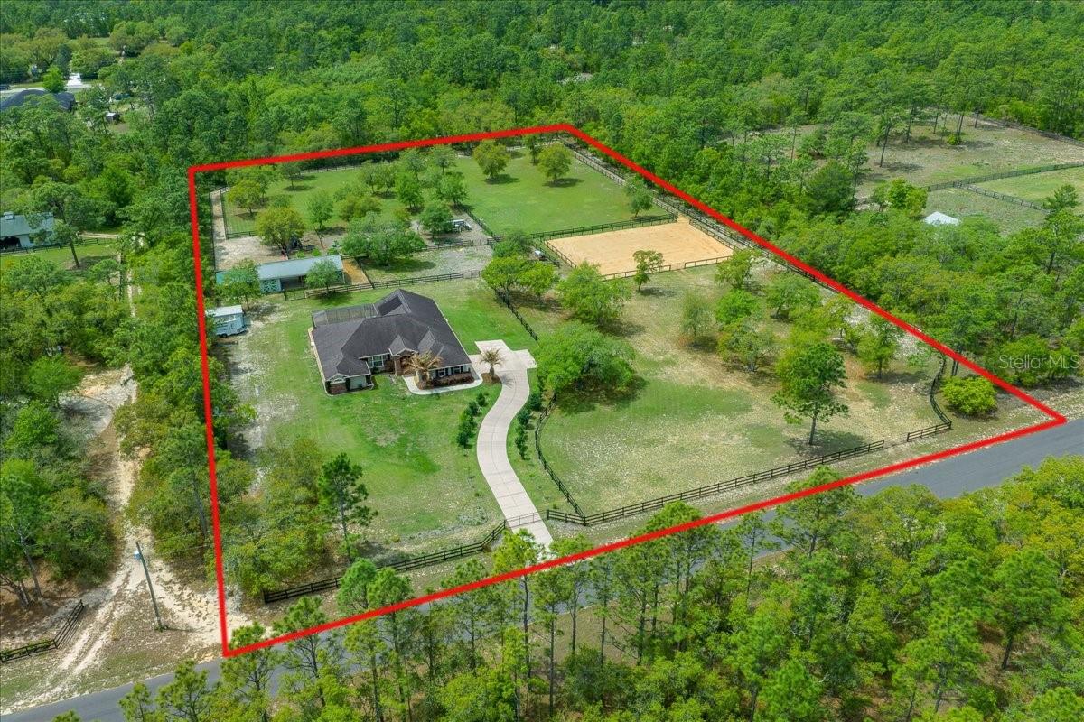 Seeking an equestrian estate with low electric bills and a homesteader’s dream setup? Look no further. This exceptional 2016 custom-built home sits on 5.51 fully fenced acres in the highly desirable equestrian community of Pine Ridge, offering access to 28+ miles of scenic horse trails. This meticulously maintained 4 bedroom, 3 bath solar heated pool home with a 2 car garage offers 2,545 sq ft of thoughtfully designed living space. Step inside to warm engineered hardwood flooring flowing through the main living areas, filled with natural light and enhanced by soaring ceilings. Dual living spaces provide both elegant entertaining areas and comfortable everyday gathering rooms. The kitchen features ample cabinet and counter space, a center island, breakfast bar seating, and a pantry for additional storage.The spacious primary suite includes French doors leading to the pool and a luxurious ensuite with double vanities, a tiled walk in shower, and a relaxing garden tub. A split floor plan offers two guest bedrooms with a shared bath, while the fourth bedroom is privately situated with its own full bath and direct pool access, perfect for guests or multi generational living. The southwest facing lanai and pool allow you to fully enjoy Florida’s sunshine year round. Equestrian enthusiasts will appreciate the well appointed setup, including a 24x48 pole barn with 2 stalls, tack room, and feed room, along with 4 paddocks and an 80x110 riding arena resurfaced in 2026. A dedicated track system for horses adds even more functionality for training and daily exercise. The barn roof is equipped with 24 solar panels powering the home, delivering outstanding energy efficiency and low electric bills. Additional exterior features include a 20x21 carport and a 12x20 shed, offering ample storage for equipment, trailers, and tools. For those dreaming of a more self sufficient lifestyle, this property already has you started with an incredible variety of established trees including blueberry, lime, lemon, apple, peach, avocado, orange, olive, grape, kiwi, raspberry, and more, all supported by their own drip irrigation system. Pine Ridge offers a true lifestyle with amenities including a community barn, arena, tennis courts, shuffleboard, parks, clubhouse, and extensive riding trails. Conveniently located near shopping, schools, and restaurants, with Gulf access for fishing and boating. The World Equestrian Center is approximately 32 miles away and HITS about 38 miles away, making it ideal for equestrian enthusiasts. Come experience everything this incredible horse property and homestead opportunity has to offer,schedule your private showing today!