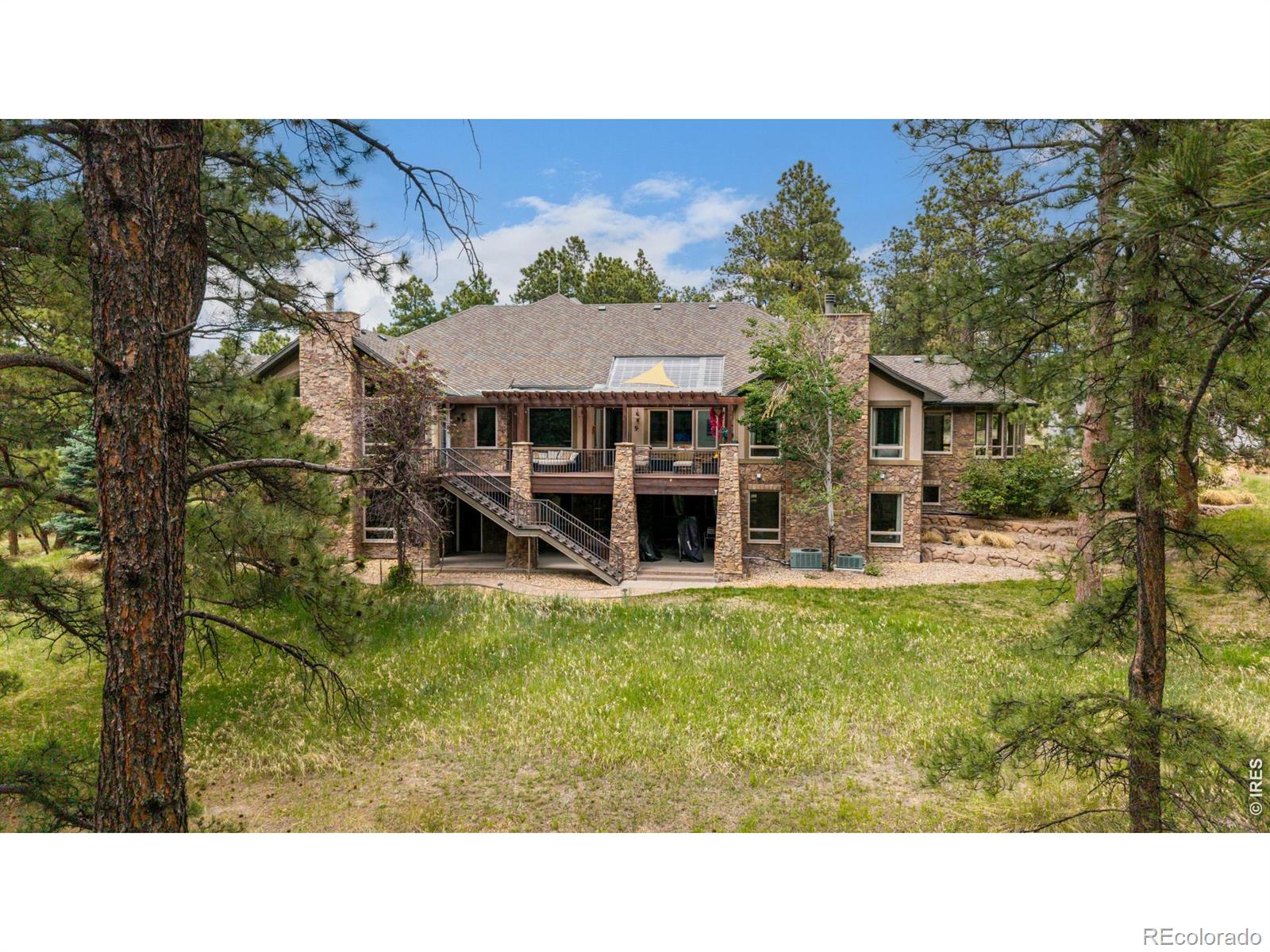 Nestled amidst nearly 20 acres of pristine Colorado wilderness, where towering pines sway above colorful wildflowermeadows, lies a retreat that feels like a world apart-yet it's just a short drive from Denver. With complete privacy, thisproperty is a sanctuary for the soul. Whether you're exploring private hiking and biking trails or perfecting your swing onthe exclusive 18-hole golf course, adventure and tranquility coexist here in perfect harmony. The 7,980-square-foot homeis a masterpiece of design, where rustic charm blends seamlessly with refined luxury. Step inside to soaring ceilings and agrand living room anchored by a stately stone fireplace, its expansive windows framing the breathtaking natural beautyoutside. At the heart of the home is a gourmet kitchen that's every chef's dream: knotty alder cabinetry, gleaming granitecountertops, double ovens, multiple islands, and a breakfast bar set the stage for everything from intimate family meals tolavish gatherings. Connected spaces like the elegant dining room, cozy breakfast nook, and wet bar flowing into the greatroom make entertaining effortless. The main-level primary suite is nothing short of a sanctuary. With its own gas fireplace,custom built-ins, dual walk-in closets, dual vanities, a jetted soaking tub, a steam shower, and a wall of windows thatinvite the outdoors in. The home's lower level is a haven for entertainment and relaxation. A walk-out basement features achic wet bar, a rec room, and a home theater, perfect for movie nights or hosting friends. Upstairs, a curving staircaseleads to a charming loft with a versatile sitting area and a perfect home office or guest suite, providing the ideal escape forvisitors or personal retreat. Here, life unfolds against a backdrop of natural splendor and sophisticated living-a perfecthaven for those who seek both luxury and nature's embrace. This is where unforgettable memories are made, and whereevery day feels extraordinary. Welcome home.