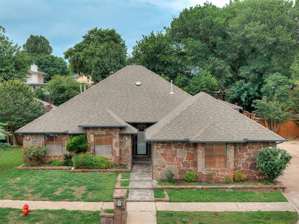 You do not come across a home like this every day. Tucked away on a quiet cul-de-sac in desirable West Norman, this distinctive property offers timeless character, unique architectural details, and a backyard setting that feels like a private retreat. With its striking all-stone exterior and abundance of mature trees, this home makes an unforgettable first impression. The interior showcases a beautiful blend of natural materials and craftsmanship, featuring stone accents, wood and tile flooring,  and thoughtful built-in storage throughout. The spacious living room serves as the heart of the home, anchored by a grand wood-burning fireplace. The functional floor plan offers flexibility for a variety of lifestyles. On the main level, you will find a comfortable primary suite along with two secondary bedrooms and a full guest bathroom. The large laundry room provides additional storage space and everyday convenience. The kitchen has been updated with stainless steel appliances and offers ample cabinetry. A beautiful wooden staircase leads to the upper level where you will discover an expansive bonus area complete with a full bathroom. Whether used as a second primary suite, guest quarters, game room, home office, media room, or additional living space, this versatile area provides endless possibilities to fit your needs. Step outside to experience one of the property's most captivating features. Backyard offers a peaceful setting with mature trees providing shade and privacy. Covered patio creates the perfect space for outdoor dining and entertaining, while decorative paver walkways allow you to enjoy views of the koi pond. Completing the outdoor space is a detached storage building that offers incredible flexibility as a she-shed, man cave, workshop,  or additional storage area. Located in a highly sought-after West Norman location close to shopping, dining, parks, and schools, this one-of-a-kind property is ready for its next owner to make it their own.