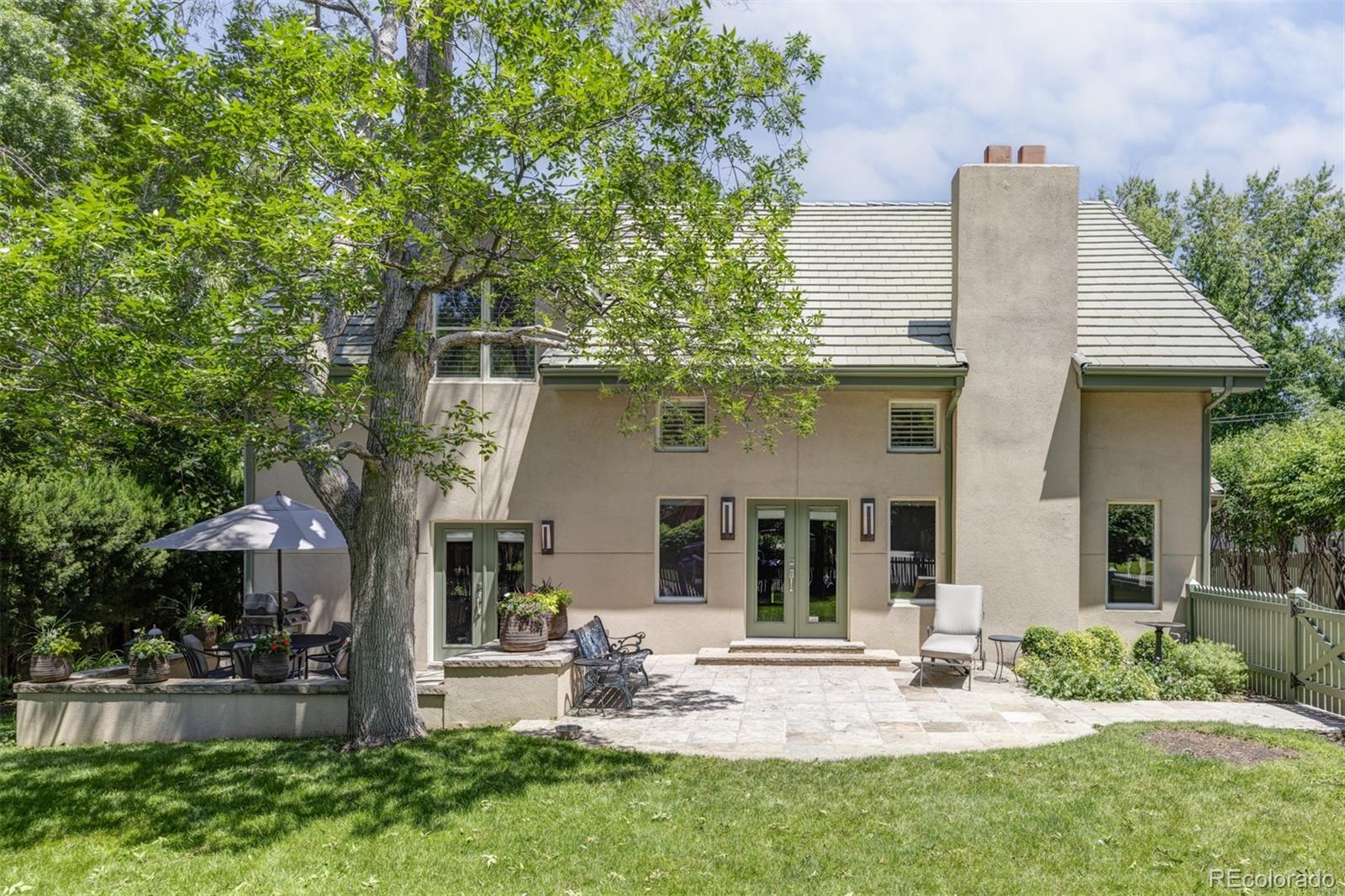 Set on a rare and expansive 10,300-square-foot lot, this distinguished Hilltop residence masterfully blends historic character with thoughtful updates across three finished levels. Originally built in 1940, the home was entirely rebuilt in 1989 and offers timeless charm at every turn. A generous entry sets a gracious tone, leading to refined living spaces including a great room with a gas fireplace, a formal dining room with French doors to the front patio and a study adorned with custom built-ins. A guest bedroom with ample closet space is adjacent to the full bathroom. The kitchen, anchored by a Wolf gas cooktop, with a butler's pantry is ideal for a coffee station or entertaining. A sun-drenched heated sunroom connects to the beautifully landscaped backyard — one of several indoor-outdoor connections throughout the main level. Upstairs, the primary suite offers built-ins, a walk-in closet and a five-piece bath with updated granite countertops and updated tile. In addition, the upstairs includes a loft/office and a large walk-in storage closet which could be converted into an additional bedroom. The partially finished basement adds a bedroom, bath and laundry room. Outside, mature trees, paver patios and a two-car detached garage with abundant storage complete this exceptional offering.  Close proximity to parks, 9th and Colorado amenities and Cherry Creek.