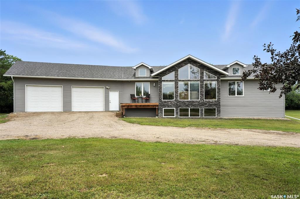 Very unique property on a gorgeous serene setting, this 1532sqft raised bungalow RTM (built stronger for transport) country home offers freedom from city noise, from large powers bills & from scary winter heating bills! Peacefully set inside 10 acres surrounded by shelterbelt trees, this home has main floor laundry & 2pce bath on tile floors close to the front entry. The kitchen has plenty of dark maple cabinets & island with breakfast bar, stainless steel appliances, gas range, pantry & vaulted ceiling extending over the dining room and living room. There is a feature stone wall dividing off the living room that has a 2 sided gas fireplace, TV mount & floor to vaulted ceiling window. There are 2 spare bedrooms & a 4pce bath on this level plus the master bedroom with dormer window, walk-in closet & ensuite with jacuzzi tub & separate all-tiled shower. The basement has a huge family room & games room, 2 more spacious bedrooms all with cozy carpets, a 3pce bath, storage room & the utility room with the brains of this unique home. This home & attached garage are heated very economically with a geo-thermal unit from MiEnergy that has two 300' loops gathering free energy for heating so you have freedom from SaskEnergy bills. There is also a 10'x80' wall of 17.02KW solar panels capable of 25,785KW of power/year which is more than acreage consumption, fed into the 200Amp house panel, panels can withstand 100MPH winds, this gives you freedom from power costs! This property also has city water on trickle system with a 1250gal holding tank, free access to Loraas garbage binyard included in property tax, Radon mitigation system, dog run, 104 yard gun range, 3 dugouts you can stock with fish or skate on in the winter, a Huge back deck, 2 firepit areas, a few steel bins & walking paths! The triple car attached garage has infloor heat plus forced air heater, laundry hookups, floor sump & dog door to dog run. House basement has infloor heat, forced heat upstairs. Great value