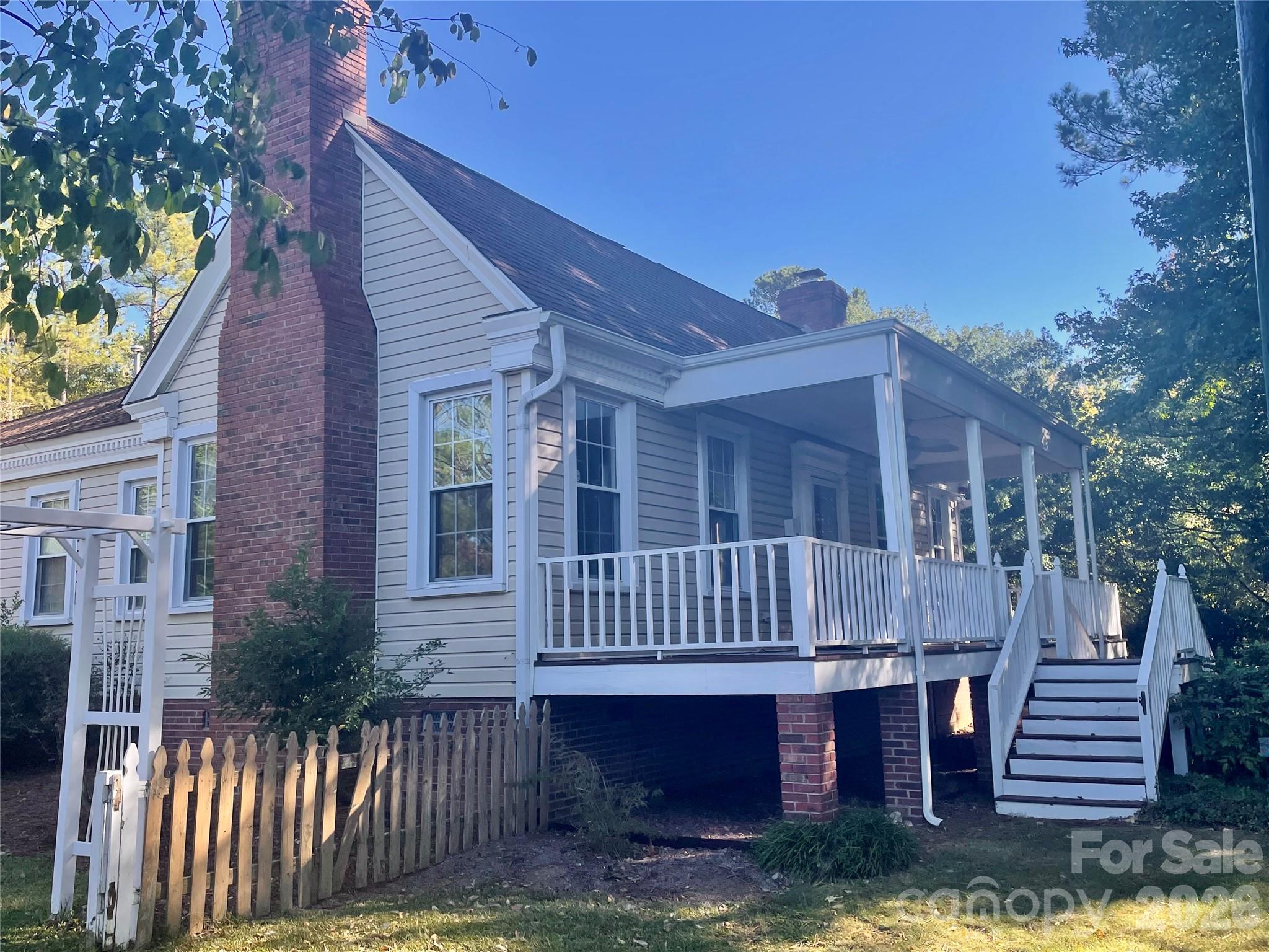 If you want to own a piece of Fort Mill history, then this is your home. You will fall in love with this charming farmhouse on 1.91 acres. This size lot is rare in our area.  Original features include: hardwood floors that glow in the gorgeous natural light – cast iron farm sink - built-in china hutch – working gas fireplace in office/flex room – bathroom tiles - glass doorknobs.  Enjoy cozy evenings in front of the gas fireplace. The primary bedroom has a dressing area with a wall of closets. Enjoy the vintage vibes on the covered front porch.  There’s plenty of space for gardening, privacy, and no HOA.  Just a few minutes to all the fun that our downtown Fort Mill has to offer. Convenient to shopping, restaurants/brewery, schools, the Greenway, and the bypass to I-77.  This home has been maintained with replacement windows, siding, roof 2008, encapsulated crawlspace, septic has been pumped and inspected. Have the receipts. The detached garage is huge, with a workshop and an unfinished upstairs. Originally built near downtown Ft. Mill, this home has been loved for several generations, and was moved from town in the 1980’s.  Home is being sold as-is.  Seller is offering $5000 to the buyer at closing.  Offered below appraised value.  Make your showing appointment now.  Photos are virtually staged. New professional photos will be taken on 10/21 and uploaded 10/22.