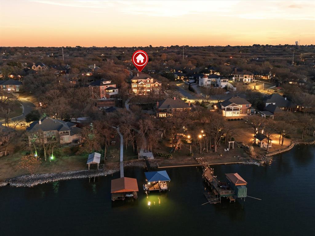 Built in 2018, this rare three-level waterfront home blends thoughtful design with functional living across every floor, all located in the highly desirable Tiffany Park neighborhood with no HOA. The main living level features an open-concept layout centered around an oversized kitchen island and spacious living room with soaring ceilings and a statement fireplace. A private guest suite with full bath and balcony access provides comfortable accommodations for visitors. A dedicated office supports work-from-home needs, while the custom bunkroom-style play space with built-in desk and extensive storage adds flexibility for everyday living.The third floor is dedicated to the bedrooms, featuring the primary suite, two additional bedrooms connected by a Jack and Jill bath, and a third living area with barn doors for added privacy. The primary suite captures elevated water views and includes a spa-inspired bath along with access to a screened patio with motorized shade. The lower level is designed for recreation and entertaining. Currently outfitted with a golf simulator and expansive living area, this level also includes a private gym and kitchenette. Direct access to the backyard creates seamless indoor-outdoor flow. Outside, the property continues to impress. A resort-style pool and spa, completed in 2022–2023, feature integrated fire elements and expansive patio space. Permanent exterior lighting enhances the home year-round. A turf putting green adds functional outdoor living. A private sidewalk leads to the waterfront boat dock, equipped with a boat lift and jet ski lift for direct lake access. Waterfront homes of this age, design, and location are rarely available. This property offers the advantage of newer construction, private boat dock access, and the freedom of no HOA in one of the area’s most desirable lakefront communities.
