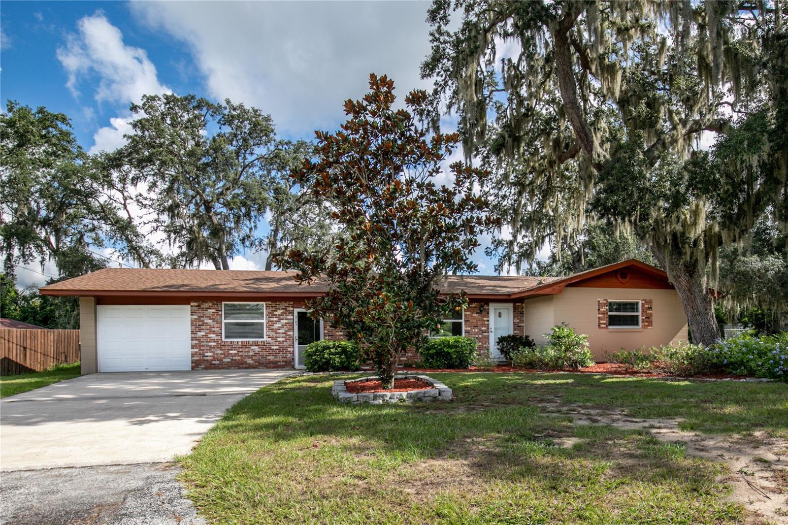 Welcome to this well-maintained 3-bedroom, 1.5-bath home in a mature Eustis neighborhood shaded by beautiful oak trees. Situated on a generous lot, the property features a 1-car garage, a spacious 20x24 detached carport, and a chain-link fenced backyard—perfect for enjoying the outdoors or accommodating pets and hobbies. Inside, you'll find a bright and tidy interior with an enclosed Florida room, a large utility/laundry room conveniently located off the garage, and a practical floor plan. The primary bedroom includes a half-bath ensuite, offering a little extra privacy and comfort. Mature landscaping adds charm and curb appeal, and a separate irrigation well helps keep everything green and thriving year-round. As a resident of this neighborhood, you'll have the option to join a community with access to Lake Joanna—a spring-fed lake known for boating and fishing. The optional fee includes access to a private park, playground, dock, and designated swimming area.
 Living in Eustis, Florida offers the best of both worlds: small-town charm with big-time convenience. Located in the heart of Lake County, you're just minutes from shopping, dining, and local festivals. Plus, with easy access to major highways, Orlando, theme parks, and Florida's beautiful beaches are all within reach for day trips or weekend getaways.