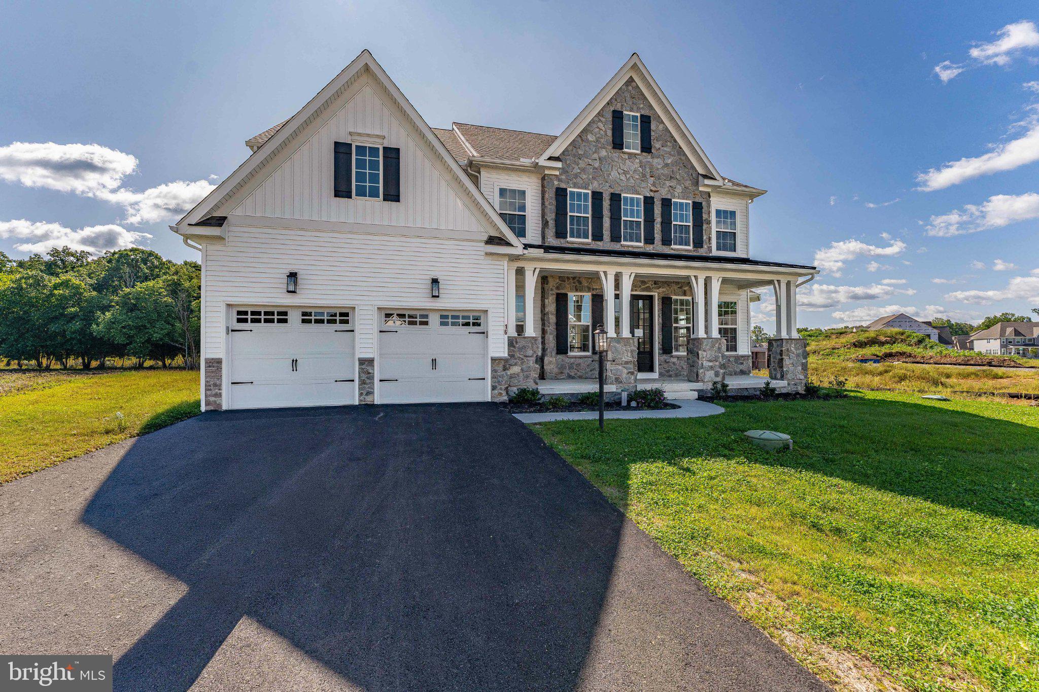 Welcome to 16 McKnight Farm Lane, a 5-bedroom, 3 full and 2 half bath home in the sought-after Trails at Marsh Creek community in Glenmoore, set within the award-winning Downingtown Area School District. Brand new and never lived in, with over 5,800 square feet including a finished lower level, it is ready for immediate occupancy with no construction timeline to wait on. Ten-foot ceilings run across the main level, and the floor plan is very flexible for a home this size. A covered front porch opens to a two-story foyer with an open staircase. The formal dining room sits under a tray ceiling with crown molding, the living room opens off the other side of the foyer, and a library nook with built-in shelving tucks in between. The family room is the centerpiece. Two stories tall with a coffered ceiling, a floor to ceiling fireplace surround, and a wall of windows that fills the space with light, it opens directly into the kitchen. The kitchen earns the attention. A chef's package delivers a 36-inch gas cooktop with vented hood, double wall ovens, a built-in microwave, glass front upper cabinets with lighting, crown molding carried to the ceiling, a farmhouse sink, and a large island with seating and pendant lighting. A butler's pantry and a walk-in pantry sit just off it, and the breakfast room opens to the rear. Beyond the family room is the sunroom conservatory, wrapped in windows under a hipped cathedral ceiling. The main level also holds a private guest suite with its own full bath and walk-in closet, ideal for an in-law suite or guests who want their own space. A mudroom entry with a built-in bench, a powder room, and interior access to the two car garage complete the floor. Upstairs, the owner's suite features a tray ceiling with rope lighting, two walk-in closets, and a spa-style bath with a freestanding soaking tub, an oversized glass enclosed shower, and a double vanity. Three additional bedrooms each include a walk-in closet and share a full hall bath with a double vanity. The laundry room is conveniently located on this level for peace of mind. The finished walk-out lower level adds more than 1,300 square feet, anchored by a cafe style wet bar with cabinetry, a sink, and a built-in microwave. A half bath and generous unfinished storage round it out, and full-view doors open directly to the backyard. Not only does this home have everything you’ve ever dreamed of, but you are minutes from Marsh Creek State Park, with quick access to I-76 and Route 322, and close to Downingtown and Exton for shopping and dining. All the benefits of new construction, without the wait. Schedule your showing today.
