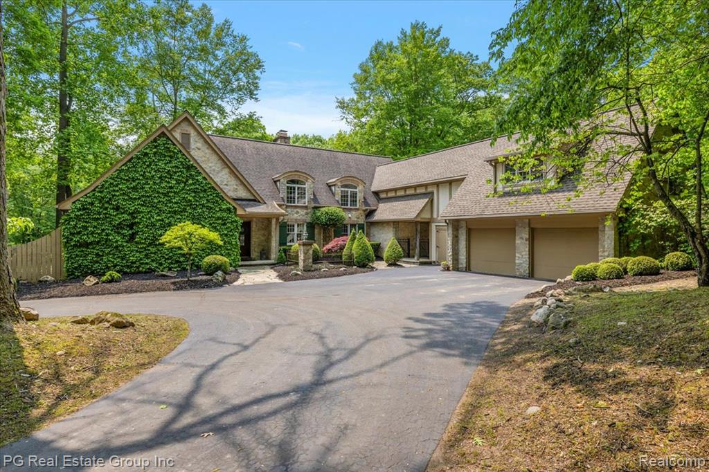 A Private Tudor Estate on 10 Acres in Oxford, Michigan. Nestled deep within 10 pristine wooded acres in the heart of Oxford, this is more than a home—it’s a private sanctuary that blends refined elegance with natural beauty. Fully renovated in 2023, this stately Tudor Revival estate offers nearly 4,000 square feet of inspired living space, a peaceful pond, a treehouse hideaway, and unmatched privacy just minutes from downtown.
Step inside to a light-filled foyer that opens into a vaulted-ceiling living room with a double-sided wood-burning fireplace. Warm hardwood floors, custom grid-style windows, and a seamless layout invite you to relax and connect. The kitchen is a chef’s dream: natural quartzite countertops, stainless appliances, and a central island perfect for prepping meals or gathering with friends. A cozy breakfast nook and coffee lounge overlook tranquil pond views.
The main-floor primary suite is a luxurious escape with private deck access, a spa-style bath, and an expansive custom closet. Also on the main level are a designer powder room, oversized mudroom with outdoor access, and a laundry room. Upstairs, two spacious bedrooms share a dual-vanity bath, while a remarkable bonus suite offers cathedral ceilings, gas fireplace, wet bar, kitchenette, and its own laundry and bath. Ideal as a second primary, guest retreat, studio, or private office.
The finished walkout basement includes space to entertain, a guest bedroom, full bath, and serene pond views.  For car enthusiasts or hobbyists, enjoy a 2.5-car attached garage and a 2400 square-foot detached garage with a heated shop, and a second-floor loft ready for customization as a guest suite, lounge, or creative space. 
This rare estate invites you to live beautifully—surrounded by nature, yet close to it all. Schedule your private tour today and experience one-of-a-kind charm.