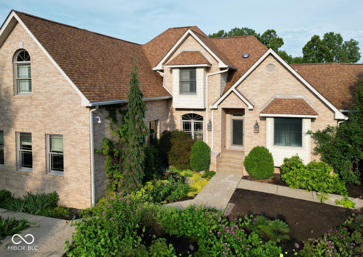 This all-brick home sits in the heart of Bloomington with a little known walking path from the neighborhood leading through the trees to the YMCA grounds accessible just across the street. Truly a fantastic location as it's near IU, walking distance to an elementary school, parks, city trails, bike paths, and so much more!  Sitting on 2 secluded at the end of a cul-de-sac, the enclosed grounds behind the home offer much privacy inside beautiful stone walls. This private recreation and entertaining area offers unique stone features, expansive walkways, stamped concrete decking, a covered outdoor kitchen/shelter house, a huge screened porch as well as a spot for a fire pit & hot tub with seating along the stone wall.  As if the outdoors isn't enough, you'll enjoy 2 separate 2 Car Garages, each with much additional storage space or room for a workshop. Offering an option of a primary suite on the main level or upstairs or both as well as 3 additional spacious bedrooms on the upper level.  Enjoy an open floor plan, amazing views, a large kitchen, breakfast room, family room, study, mud room and 3 laundry hook-ups all on the main level!  The upstairs primary is an actual suite separate from the other bedrooms and it features a personal living room space with fireplace, a large bedroom, 2 walk-in closets and a spa like en suite bath.  The expansive lower level is great for entertaining with a large family room, bedroom,  hobby room with a nice sink area, and another room that would be great for the gamers of the house. Gardeners will love the attached greenhouse! Solar panels, skylights, an enormous storage room/workshop with outdoor access are just some of the additional amenities.  A detailed list of additional amenities, finishes, and specifications are attached.
