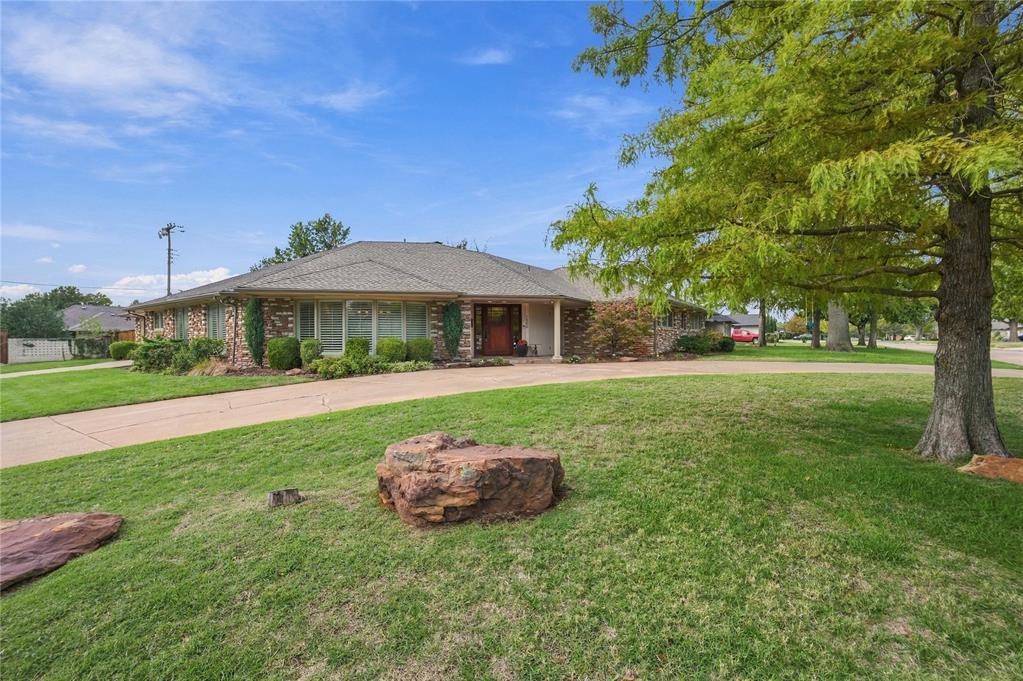 Stacked stone, mature trees, and a circular drive set the tone at this corner-lot ranch in the Waverly/Nichols Hills area, just minutes from Oklahoma City Golf & Country Club, Nichols Hills Plaza, and Classen Curve. Built in 1959 and thoughtfully updated, the home pairs architectural character and solid bones with today's comforts, including a 2025 roof with Class 4 impact-resistant shingles, new gutters, Pella and Milgard windows, dual-zone HVAC, and tankless hot water. Inside, hardwood floors, crown molding, skylights, and plantation shutters carry through an open plan with distinct, comfortable spaces. The formal dining room and front living area wrap around a curved bay of windows. The living room centers on a wood-burning stone fireplace flanked by built-ins, with sliding glass doors to the patio. The kitchen offers granite counters and backsplash, custom cabinetry with glass-front uppers, a gas cooktop under a stainless hood, built-in wall ovens, and a sunny breakfast nook. Steps away, the wet bar has a wine cooler, espresso station, and glass shelving for easy entertaining. The primary suite includes a sitting area, a custom walk-in closet with a center island, and a bath with a dual vanity, glass-tile accents, and a skylight. Every bedroom has its own en suite bath. A flexible bonus room and a laundry room with built-in cabinetry round out the interior. Out back, a heated saltwater pool with a cover and a separate spa sit beside an expansive pergola with string lights and ceiling fans, with room to grill and gather behind a full wood fence. A sprinkler system, security system, two-car attached garage, and storage shed add everyday convenience. A rare chance to own a home with real character, thoughtful updates, and one of the best locations in northwest Oklahoma City.