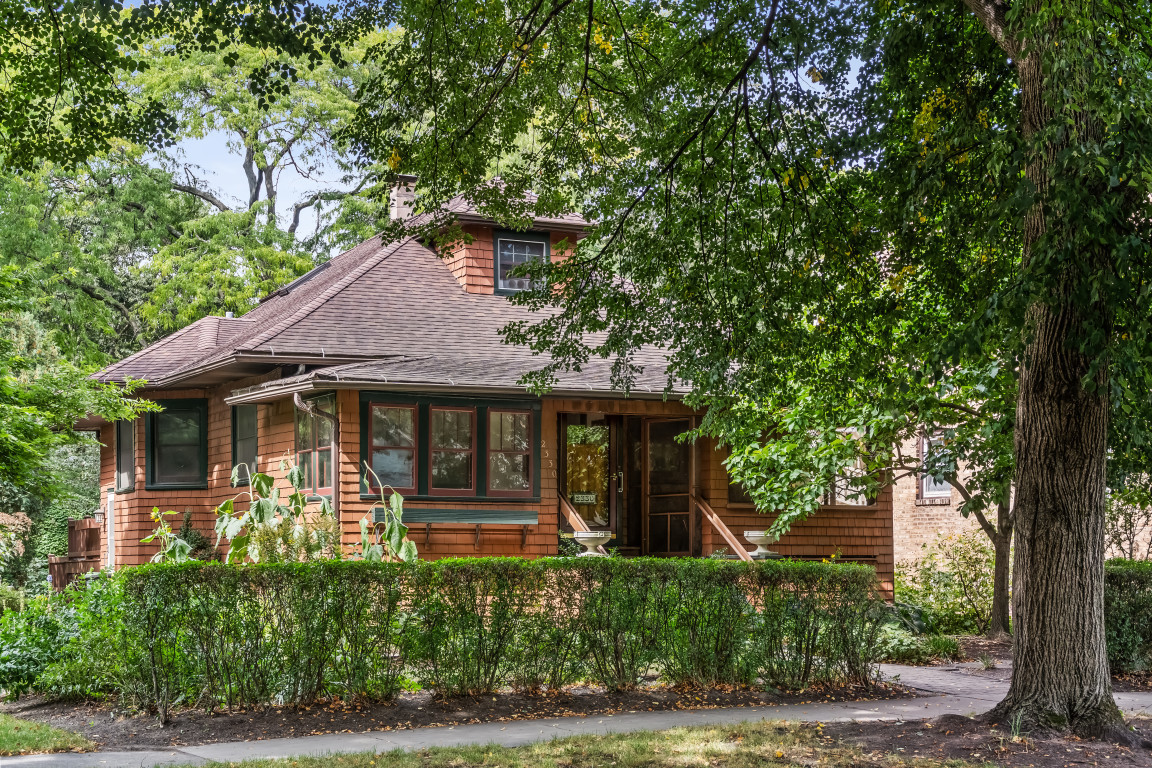 Classic 1907 Arts and Crafts bungalow in northwest Evanston, offering 3 bedrooms, 2 full bathrooms, and a rare combination of original character and thoughtful updates on a beautifully landscaped, oversized lot. Walk to Central Street shopping, dining, the Metra commuter train, and parks, with easy access to Northwestern University and Lake Michigan. A distinctive cedar-sided exterior sets the tone, while original fir hardwood floors and wood trim throughout the main level showcase the home's authentic character. The foyer opens to a welcoming living room and formal dining room, plus a versatile office/den with wood floors and windows on two sides. A dreamy screened porch flanks the foyer also. The kitchen, renovated by Seigle Kitchen Designers, features Decora hickory cabinetry extending to the ceiling, laminate countertops, dual sink areas, and updated electrical and plumbing. An addition by Normandy Building created a spacious family room anchored by a wood-burning fireplace, oak parquet flooring, custom built-in bookcases, and a large bay window. The main-level primary bedroom features diamond leaded glass windows restored by Botti and hardwood flooring, alongside a second main-level bedroom and a fully renovated bathroom with a pedestal sink and tiled tub surround. A third bedroom and full bathroom occupy the upper level. The full basement under the original house includes a recreation room, utility room, storage room, and workshop, with additional insulated crawl space beneath the family room addition. Outside, professional landscaping by Nature's Perspective fills the expansive lot with mature perennials, redbud trees, witch hazel, and viburnum. Two decks extend the living space outdoors, and a detached garage offers off-street parking. Additional updates include a newer water heater. Decades of ownership and hands-on care are evident throughout - from the hand-stripped original trim to the carefully maintained mechanical systems - offering a buyer a rare, move-in-ready piece of northwest Evanston history, just steps from all the Central Street corridor has to offer.