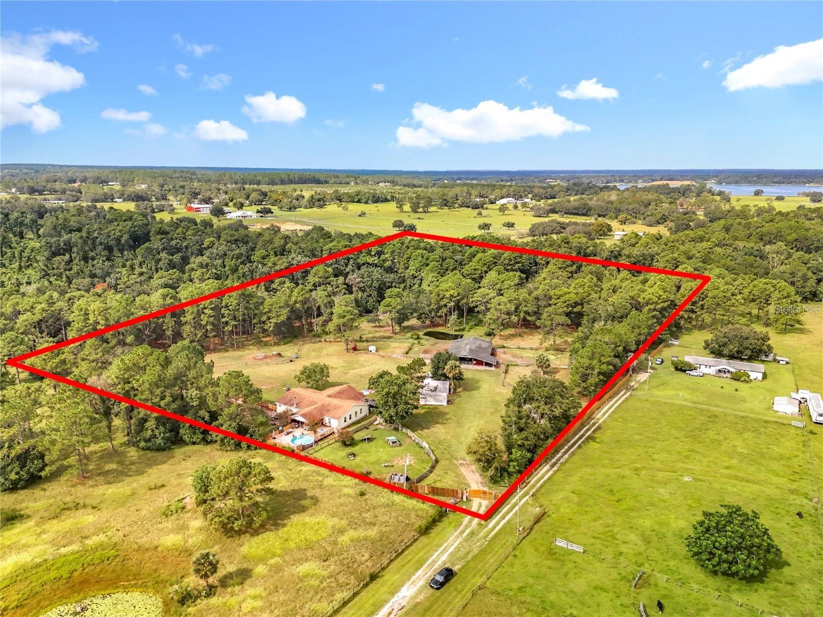 MOTIVATED SELLER! Welcome home to your new legacy inspired property! This home is priced BELOW CURRENT APPRAISAL & IS READY FOR YOU TO CALL HOME! Situated on almost 13 acres COMPLETELY FENCED, this property not only has a MOVE IN READY 4 bedroom 3 FULL BATH HOME WITH OVER 3000 sqft of living space, but room to expand! Walk in the front door & immediately be greeted by an open floor plan that is PERFECT for family gatherings! A wood burning fireplace for cooler evenings is just one of the cozy features this home features, along with a HUGE kitchen area with newer stainless steel appliances, an oversized walk in pantry, a farm style sink, CUSTOM LIGHTING not only in the great room but throughout the home as well. Have your pick of using the 2 bonus rooms as bedrooms, offices, playrooms and more! The possibilities are ENDLESS! This home family owned & loved & you will feel this the moment you walk through the front door. Whats fantastic is walking out the back sliding doors into your literal own OASIS! The enclosed back porch opens up onto a CUSTOM 33 x 50 deck surrounding the sweetest pool adorned with personal touches, trees, a new sand pump & More! Its like your laying out in the mountains with the perks of the Florida sun! The property is literally READY for your horses, chickens & More, & is equipped with chicken coops, 3 sheds for storage, a 3700 SQFT, 8 STALL BARN (EACH 12 X14 IN SIZE) FEATURING A 10 X 14 FEED & TACK ROOM, enclosed fenced area for horses, a fenced in back area currently being used as a kennel w/multiple custom dog house. A whole house water softner system that conveys, a newer roof done in 2018, & a remote controlled gate to let guests in & out, & MORE! THERE IS JUST SO MANY PERKS TO THIS PROPERTY IT IS TOO MUCH TO CONVEY! DID I MENTION THAT THERE IS 25 ACRES BETWEEN YOU AND THE NEXT HOMEOWNER & THE COUNTY SAYS YOU CAN BUILD ANOTHER DWELLING UP TO 2100 SQFT ON THE PROPERTY? LITERALLY BUILD A LEGACY PROPERTY FOR YOUR LOVEDONES! Let this property be YOUR NEXT FOREVER HOME!