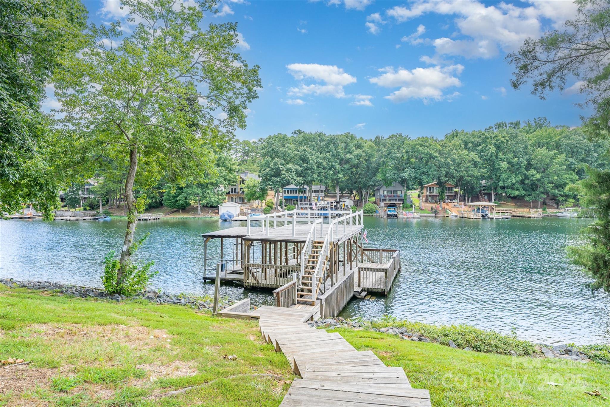 Tucked away in a deep-water cove, this stunningly renovated 4-bed, 3-bath lakefront retreat is the ultimate escape. 100 feet of lake frontage, this home captures the essence of lake living with panoramic water views and modern luxury throughout. Step inside the open-concept layout, soaring vaulted ceilings and elegant finishes at every turn. The gourmet kitchen features custom cabinetry, quartz countertops, a massive island and luxury vinyl plank flooring that flows seamlessly into the bright living space. The spa-like bathrooms showcase marble tile and refined fixtures, while the stylish cable railing adds a contemporary touch throughout the home. A dedicated bunkroom is perfect for hosting guests or kids’ sleepovers, and the brand-new outdoor shower is ideal after a day on the water. Enjoy your mornings on the screened porch and your evenings on the double-slip covered dock with lifts, soaking in the sunset views over the lake. This lakefront gem offers the best of Badin Lake living.