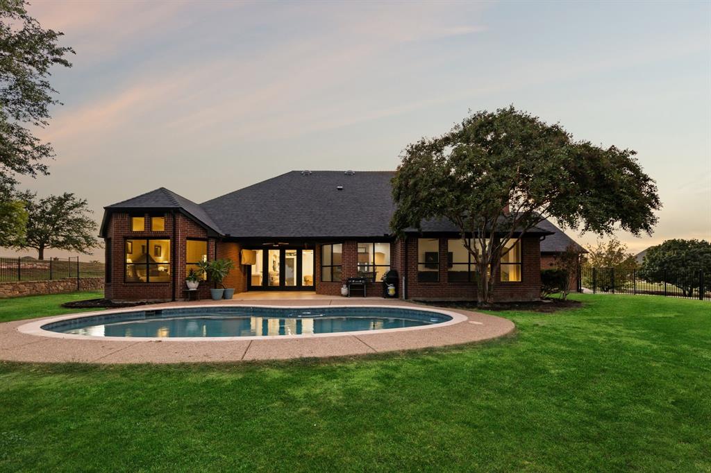 Perched on a hilltop in the gated community of Lago Vista at Bonds Ranch, this beautifully updated one-story home offers peaceful living with unbeatable access to modern conveniences. Just minutes from the brand-new Eagle Mountain High School and scenic Eagle Mountain Lake, this property combines serene surroundings with everyday ease. Set on a full acre, the home features a sparkling pool, an oversized covered patio perfect for entertaining, and sweeping views of the surrounding area. Inside, the open-concept layout is filled with natural light and anchored by a spacious living room with a cozy fireplace overlooking the backyard. The kitchen opens seamlessly to the living and dining areas and is equipped with granite countertops, an island with breakfast bar, walk-in pantry, and built-in microwave. The thoughtful split floor plan includes 4 bedrooms, 3 full bathrooms, and a 3-car garage with an oversized driveway large enough to park your boat. The private primary suite boasts a large walk-in closet, dual vanities, soaking tub, and separate shower. A secondary bedroom offers an en suite bath—ideal for guests or multigenerational living—while the remaining two bedrooms share another full bathroom. Recent upgrades (May 2025) include new interior and exterior paint, updated lighting and plumbing fixtures, a new roof, refreshed landscaping, improved fencing, and a deeper-set waterline. Enjoy the best of both worlds: tranquil living just 5 minutes from the lake, 25 minutes to downtown Fort Worth, 35 minutes to DFW Airport, and only 10 miles from the shopping, dining, and entertainment options at Alliance Town Center—including Costco and more. Community amenities include gated access, fishing ponds, playgrounds, swimming pools, and walking trails. Don’t miss your chance to enjoy the quiet of the countryside without sacrificing city convenience.