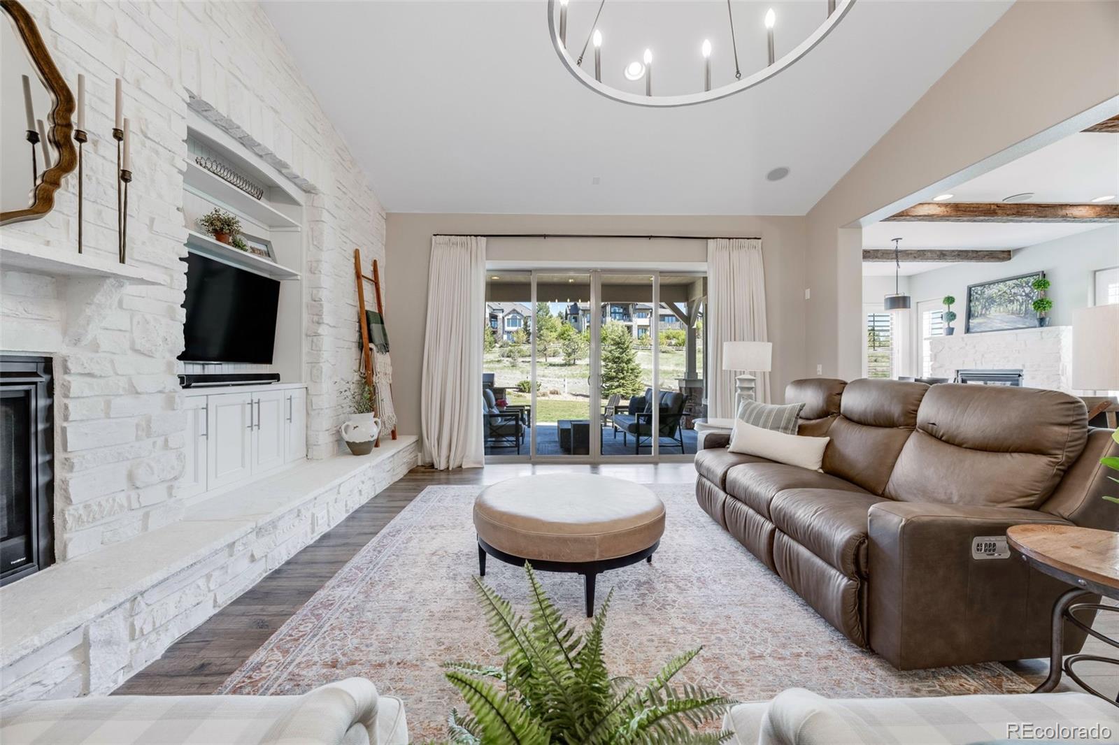 Situated on a corner lot that backs to open space in the Backcountry neighborhood, this exceptional ranch-style residence blends comfort and thoughtful design. From the moment you arrive, the home’s curb appeal and beautifully landscaped exterior set the tone. Step through the front door into a warm, inviting foyer that opens to curated living spaces. A bright main-floor office features French doors, soaring ceilings, and custom built-in shelving—perfect for remote work or creative pursuits. Guests will enjoy a private retreat at the front of the home with a spacious bedroom and attached 3/4 bath. The formal dining room is elegant with crown molding and direct access to a butler’s pantry with beverage fridge, ideal for entertaining. The heart of the home is the well-appointed kitchen, featuring white cabinetry, gas cooktop, newer refrigerator, and a large island perfect for gathering. A cozy fireplace anchors the eat-in area, which flows into the vaulted living room with a white-washed stone fireplace and a wall of sliding doors that open to the backyard oasis—complete with built-in grill, patio space, and open views. The primary suite offers vaulted ceilings, patio access, an updated 5-piece bath, and custom walk-in closet. Descend the elegantly curved staircase, accented by a modern iron railing, the finished lower level includes a wet bar with a beverage fridge, another fireplace, spacious home gym, two bedrooms, and a full bath. Whether you’re entertaining guests or working from home, or simply seeking a peaceful retreat that balances modern amenities with natural surroundings, this stunning 4-bedroom, 4-bathroom home truly delivers, from the layout to the finishes and the location that offers access to exceptional neighborhood amenities, including pools, trails, parks, and scenic open space; this is more than just a house—it’s a lifestyle! This remarkable home is one that the most discerning buyer will undoubtedly fall in love with.