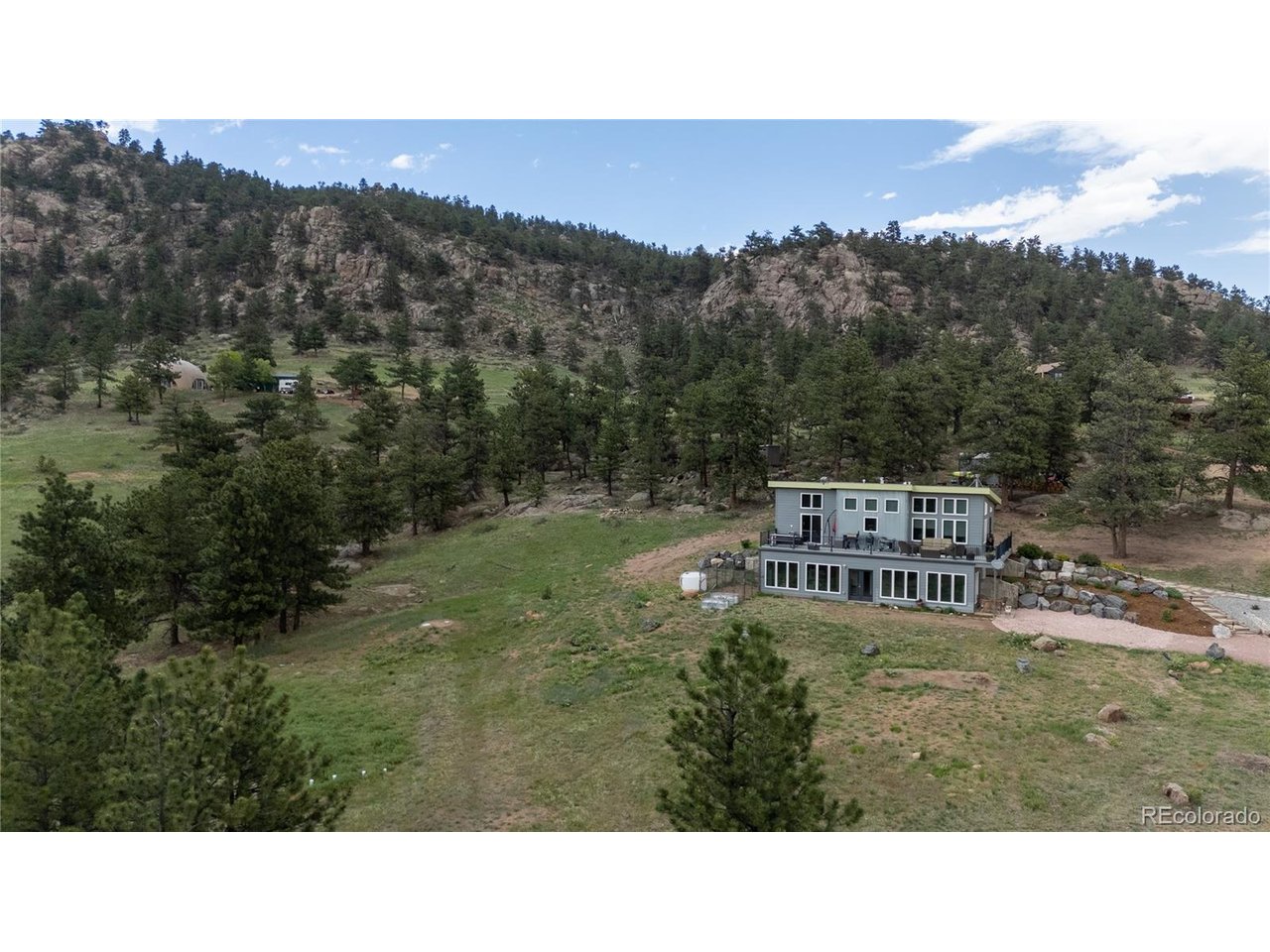 Simplify your life and escape to this 6-acre, covenant-free mountain retreat showcasing breathtaking views from sunrise to sunset, including the city lights below, offering an easy commute to Boulder, Longmont, or Estes Park. This highly efficient 2,300 sq. ft. ICF home offers an optimized layout, high-end finishes, a detached 24x36 shop, two sheds, and exceptional infrastructure for both pets and outdoor hobbies. The home features passive solar & concrete durability as it's built with ICF (Insulated Concrete Forms) and cement siding for premier energy efficiency, fire resistance, lower insurance premiums, and low maintenance. ICF costs 10-20% more than traditional wood frame construction, it offers a lifetime of durability and energy efficiency that makes it worth the extra cost. Designed with a unique magnified "tiny home" concept, it maximizes every square inch, with zero wasted space and no hallways. Enjoy two-zone air conditioning & heating, partial automated blinds, with electrical roughed in for the rest. High-end features such as granite countertops, under-cabinet lighting, soft-close cabinet upgrades with pull-outs, and a hidden safe room. Large beautiful sunroom, perfect for a reading nook, exercise room, and/or a play room. It includes a dog run with a cement foundation to keep unwanted critters out and an automatic doggy door. The well tests 5 gpm. Looking to future upgrades, the 6 usable acres could easily be set up as a potential horse property, electrical has been roughed in for a hot tub, and a concrete foundation has been laid for a chicken coop.  Dreaming about having a large shop?  The 24x36 garage/shop includes loft storage for all of your gear and projects and boasts a retractable motorized lift for getting items up to the loft, as well as two oversized garage doors (9' and 14' tall). The Private Road is maintained by a Community Road board for an annual fee of only $480. Come home to the peace and beauty that this amazing property offers!