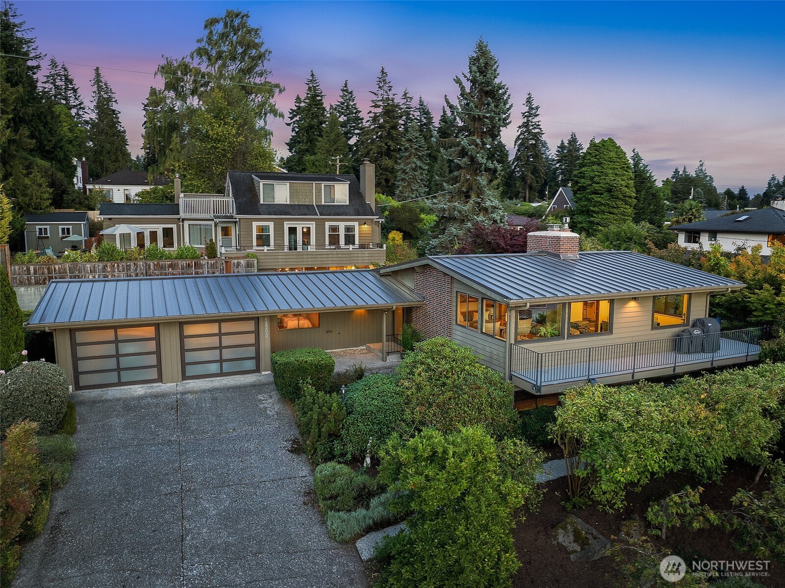 Fall in love with the timeless architecture of this meticulously maintained and thoughtfully updated home in the heart of Broadview. Beautiful sunsets, Olympic Mountain views and glimpses of Puget Sound unfold through large west-facing windows. Hardwood floors flow through the light-filled living and dining spaces, where vaulted ceilings, exposed wood beams and expansive windows create a warmth and character that feels distinctly Northwest. The updated kitchen features a Viking range, new refrigerator and direct access to the deck - an inviting extension of the living space for morning coffee, summer dinners and evening sunsets. Three bedrooms are thoughtfully situated on one level, while the lower-level rec room offers flexible space for an office, gym or media room. Major improvements include a 50-year metal roof, rebuilt chimney and new masonry cap (2023), new water service line and living room windows (2022), new heat pump with A/C and fresh exterior paint (2025). Mature landscaping creates a peaceful, private setting, while a two-car garage connected by a covered breezeway adds convenience and charm. Minutes to Carkeek Park and Beach with convenient access to Hwy 99. A special home that brings together character, space, flexibility, and privacy.