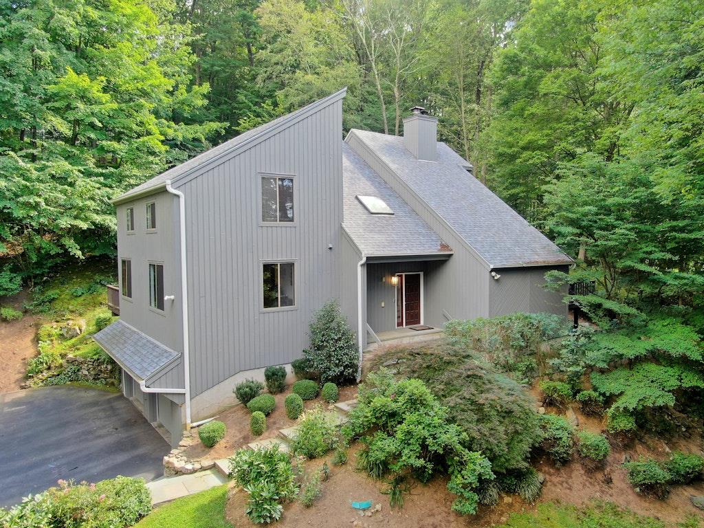 A dramatic and stunning four-bedroom Contemporary home set on 1.2 professionally landscaped acres, designed by Jan Johnsen, former landscape architect for the New York Botanical Gardens. Surrounded by wooded privacy, this serene setting features two separate decks and a ground-level patio that surrounds the exterior of the home. Inside, this home offers a light-filled, modern, and open layout with a seamless connection to nature through its soaring ceilings, skylights, and windows. The main living area features both living and family rooms, separated by a custom wood-burning fireplace and dual access to the large deck that runs along the side of the house. The eat-in kitchen is outfitted with heated floors, soapstone countertops, stainless steel appliances, and direct access to a second deck, ideal for grilling or your morning coffee. A formal dining room, two-story entry foyer, powder room, and a convenient laundry area with patio access complete the first floor. Upstairs, the primary suite includes a walk-in closet and a completely renovated en-suite bath. Three additional bedrooms and another full bath. Additional highlights include hardwood floors, modern brushed nickel switch plates, upgraded interior doors, and modern lighting. Nest cameras and thermostats, roof and skylights (2021). The unfinished basement provides storage or potential for future customization, with direct access to a two-car garage. Located near schools, shops, and just a short drive to the Chappaqua train station, this home offers a rare combination of privacy, space, and modern comfort.