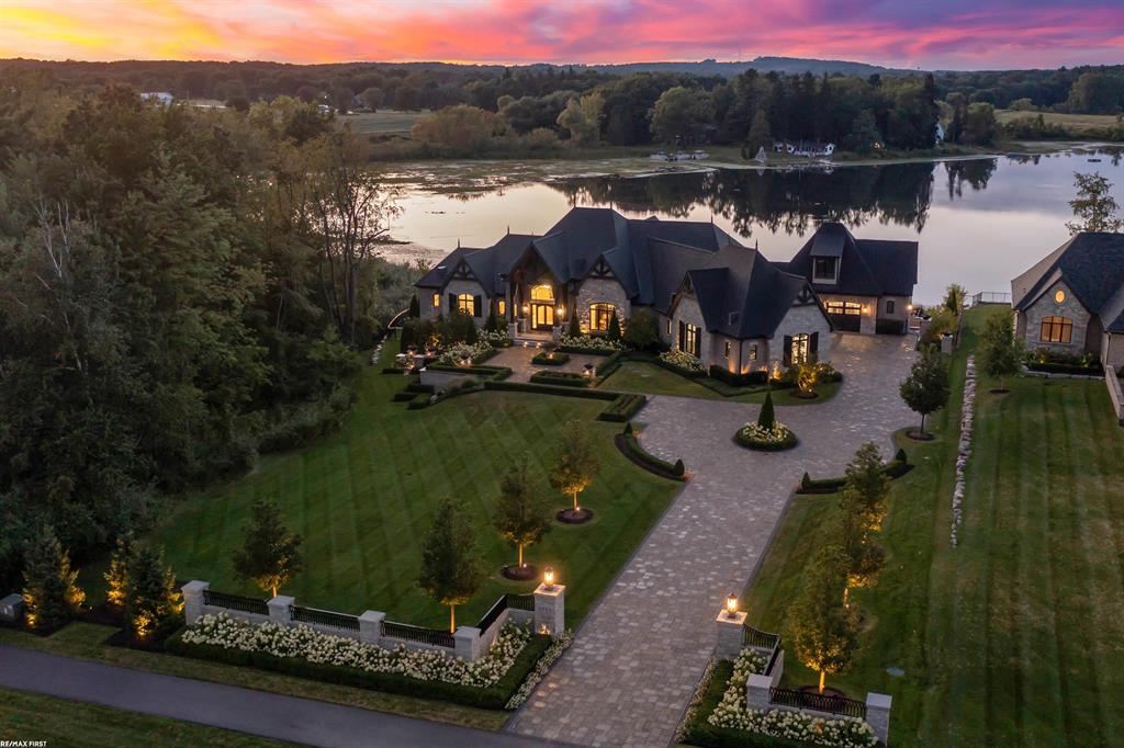 Be prepared to be amazed by this extraordinary split-level lakefront estate, designed to surly impress. Enter through the grand foyer, open to the great room with gorgeous timber beams accenting the tall cathedral ceilings. Cozy up next to the gas fireplace while overlooking the serene all-sports Cusick Lake. The open concept kitchen is every homeowner's dream, with top of the line Sub Zero, Wolf, and Miele appliances, quartz countertops, ample cabinet space, a large walk-in pantry with convenient steam oven, and a massive island with barstool seating. The four-seasons room is sure to be your favorite retreat, offering heated floors, a cozy gas fireplace, and wall-to-wall views that invite you to relax with a book or sip your favorite beverage all year-round. Just steps away, the butler's pantry provides a wet bar, ice maker, mini fridge, and a built-in Miele coffee station with cup warmer. The first-floor primary suite is a true sanctuary with dual walk-in closets and a spa inspired ensuite featuring floating vanities, dual sinks, a standalone tub, and an expansive walk-in steam shower. Upstairs, three additional ensuite bedrooms provide privacy and comfort, each with spacious closets offering built-in shelves. First floor and second floor laundry provides added convenience for day to day tasks. The finished walk-out lower level is nothing short of spectacular, showcasing coffered ceilings, hardwood floors, a gas fireplace, and a second full kitchen. Highlights include a private home office (or additional bedroom), coffee bar, one full and one half baths, gym, sauna, and a hidden safe/gun room. Entertain in style in the unique wine and bourbon lounge, showcasing custom timber beams. A secret poker/cigar lounge with an advanced air filtration system awaits to host game/poker nights with friends and family. Step outside to your private fenced-in oasis! Dip your toes in the sand at your own private beach along the water's edge, or enjoy the elegant built-in 20x30 gunite heated pool offering peaceful fountains, jets