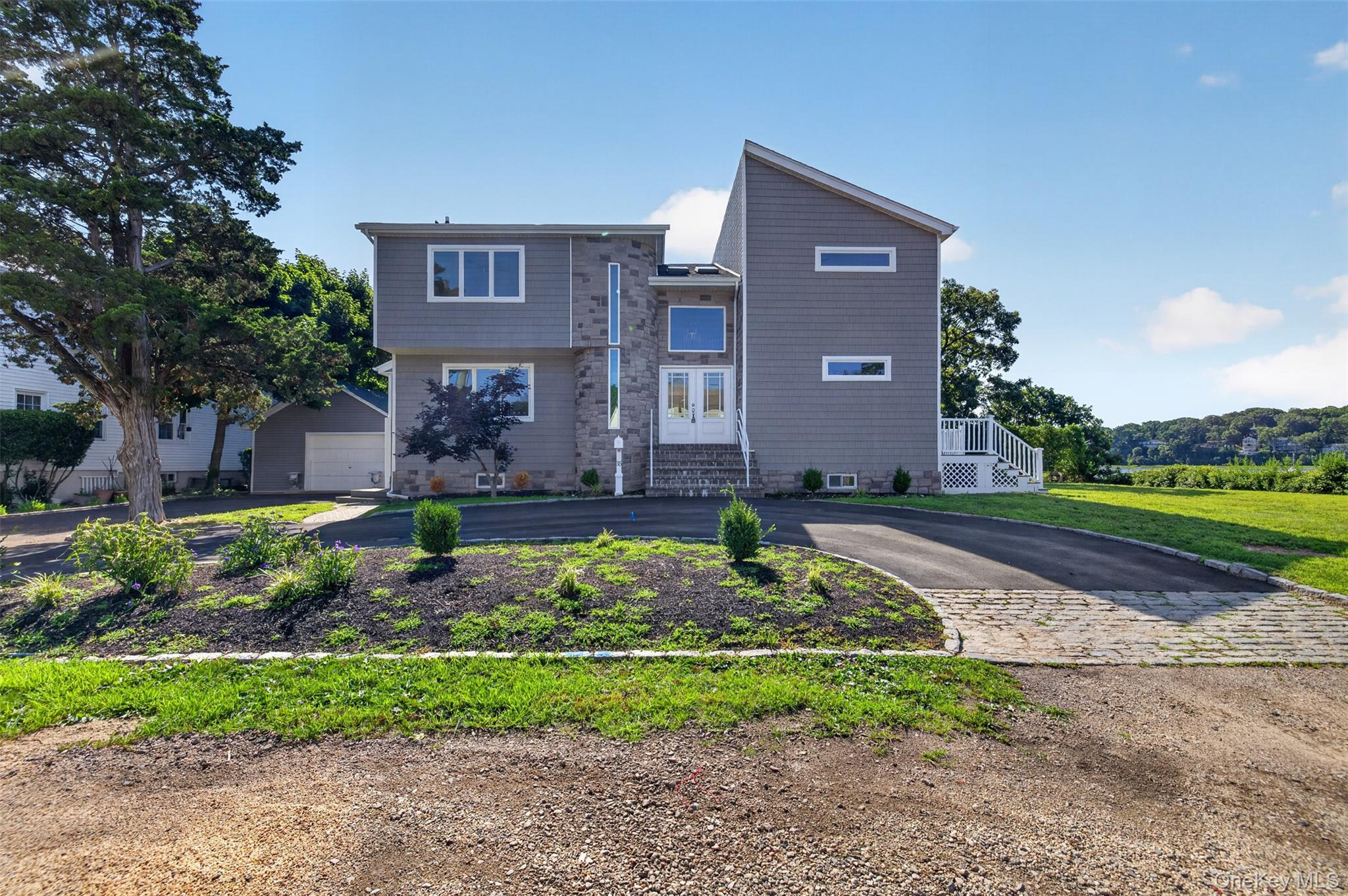 Experience coastal luxury in this fully renovated 4 bedroom, 3 bath waterfront Contemporary Colonial in Bayville. Designed to maximize breathtaking water views, this exceptional home features an open-concept floor plan with walls of glass that fill the interior with natural light and showcase this stunning shoreline.  Great room has new sliders overlooking water and a striking stone fireplace serves as the focal point of the main living space creating the perfect setting for entertaining or relaxing year round.  The gourmet kitchen is beautifully appointed with center island, quartz countertops, custom shaker cabinetry and a full suite of high-end appliances. First floor also includes lovely French doors seamlessly flowing into the spacious living and dining areas and a half bath.  Second level has 4 large bedrooms, 2 full baths and laundry area. Retreat to the spectacular primary suite featuring vaulted ceilings, a dramatic wall of windows overlooking the waterfront, and direct access to a private waterfront deck  - your own personal sanctuary to enjoy morning coffee or evening sunsets.  Primary bath features vaulted ceilings, huge separate shower, soaking tub, double sinks, space age toilet and recessed lighting.  Additional features include high-tech ceiling fans and radiant heat in several rooms. Outdoor living is unparalleled with new stone front, all new siding, a new roof, circular driveway and expansive new Trex decking on both the first and second levels, offering multiple spaces to take in the panoramic water views.  Launch your kayak right from your backyard and embrace the waterfront lifestyle.  As an added bonus, enjoy access to a private beach on the Long Island Sound side, where picturesque sunsets paint the sky each evening.  This rare Bayville waterfront gem combines modern luxury, thoughtful design, and an unbeatable location delivering the ultimate year round vacation lifestyle.  A truly extraordinary opportunity not to be missed.