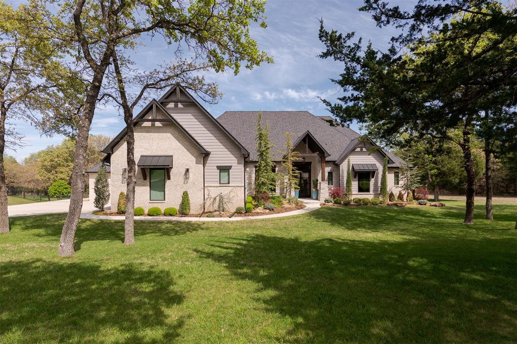 Welcome to Mystic Valley, 1.95 beautiful, wooded acres and pond in the serene Grand Timber community. This stunning transitional style home has 4 bedrooms, 4.1 bathrooms, and the perfect blend of openness and private retreats for exceptional living. Upon entering, you are greeted by natural light highlighting spacious living with 12’ ceilings, expansive rooms, and impressive designer finishes. Walls of windows showcase views of the private pond, mature trees, and manicured landscape. The well-designed kitchen features crisp white cabinetry, quartz counters, a dedicated pantry for counter appliances and additional storage, and a generous center island ideal for gathering. Just steps away, the butler’s pantry offers an additional serving area and 10’ high cabinets with lighted glass front uppers. The open living area impresses with cypress wood beams, a striking stone fireplace, custom built-ins, white oak hardwood floors, and gorgeous views. The spacious primary suite includes dual vanities, a separate makeup vanity, separate walk-in closets, and a freestanding tub against a full tile accent wall. A large study, versatile flex room with wet bar and wine fridge, and all bedrooms are conveniently located on the first floor. The second floor features a full bath and optional bonus room, second flex space, or fifth bedroom. Every room, closet, and bathroom offers generous space and thoughtful design. Enjoy peaceful outdoor living with the expansive covered patio, wood burning fireplace, and the occasional deer. Impeccably cared for, this home feels like new and is truly move-in ready. Ask your realtor for the extensive list of features and schedule your private showing today!