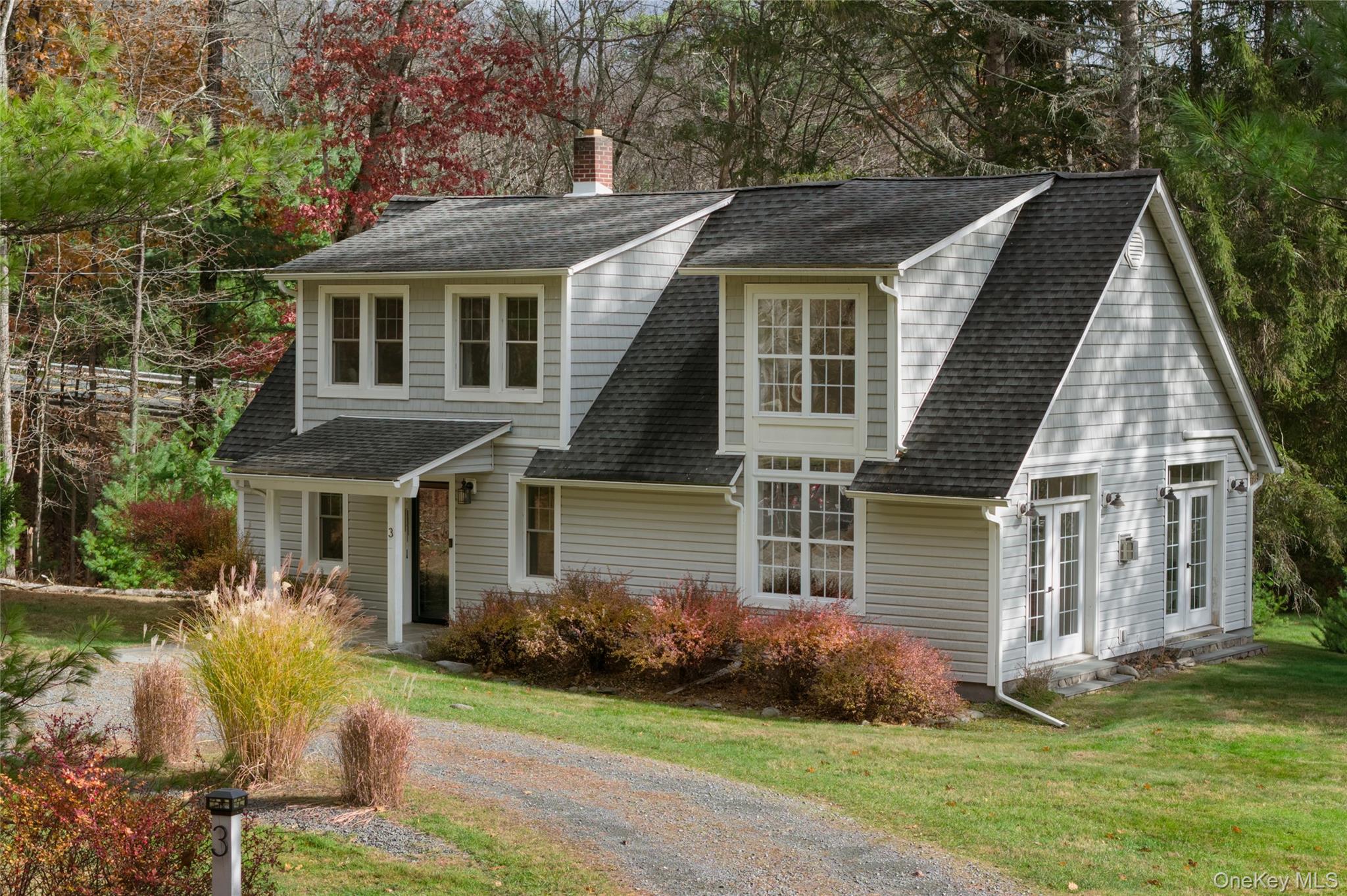 View of front facade featuring a chimney, roof with shingles, and a front lawn
