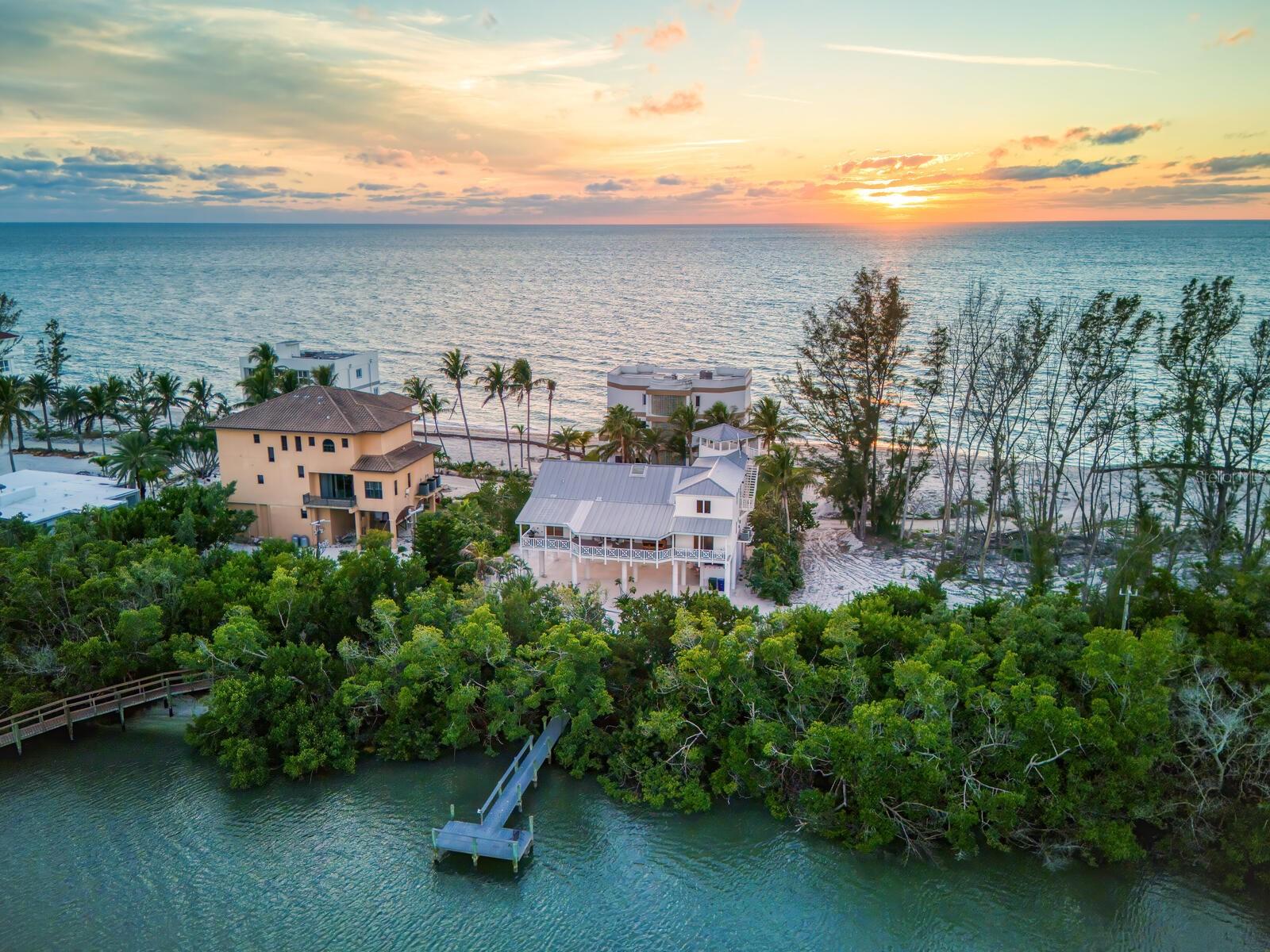 Gulf-to-Bay elegance meets relaxed coastal sophistication in this elevated, sailboat-access waterfront retreat, ideally positioned within one of Siesta Key’s most exclusive gated enclaves. Set in a rare peninsula neighborhood offering true Gulf-to-Bay living, this Caribbean-inspired residence delivers exceptional privacy, sweeping water views, and direct boating access with no bridges to the Intracoastal Waterway. With the newly reopened Midnight Pass just minutes away, access to the Gulf is effortless, making this an extraordinary opportunity for boaters and beach lovers alike.Surrounded by mature tropical landscaping and located on a quiet dead-end street, the home enjoys both Gulf views and a tranquil basin setting with a private dock. Inside, a vaulted-ceiling great room anchors the main living level, filled with natural light and framed by sliding glass doors that open to expansive covered terraces on both the east and west sides—perfect for sunrise mornings and sunset evenings overlooking the water. The open-concept kitchen is designed for entertaining and everyday living, featuring premium appliances including a Sub-Zero refrigerator and generous workspace.The primary suite is located on the main living level, offering terrace access and serene water views, while additional guest accommodations provide flexibility for family and friends. Above, a rooftop observation deck—accessible via spiral staircase—offers breathtaking 360-degree vistas spanning the Gulf, bay, and coastline, creating a truly unforgettable vantage point.Thoughtfully constructed on pilings with storm-conscious design, the home blends timeless island style with peace of mind. The ground level provides covered parking for multiple vehicles, abundant storage, and space for kayaks, paddleboards, and beach gear. An elevator shaft is already in place for future installation, and pool plans are available.With deeded beach access just steps away and a private dock at your back door, this is one of the few properties on Siesta Key where you can enjoy the beach in front and your boat behind. Beach, boating, privacy, and views converge in this exceptional offering—capturing the essence of Gulf-to-Bay living on Siesta Key. From morning experiences along the shoreline to breathtaking sunsets over the Gulf, every day on Siesta Key feels like a vacation. And when you're ready to explore beyond the island, downtown Sarasota is just a short drive away, offering world-class dining, arts and culture, including the Ringling Museum, Van Wezel Performing Arts Hall, and St. Armands Circle.