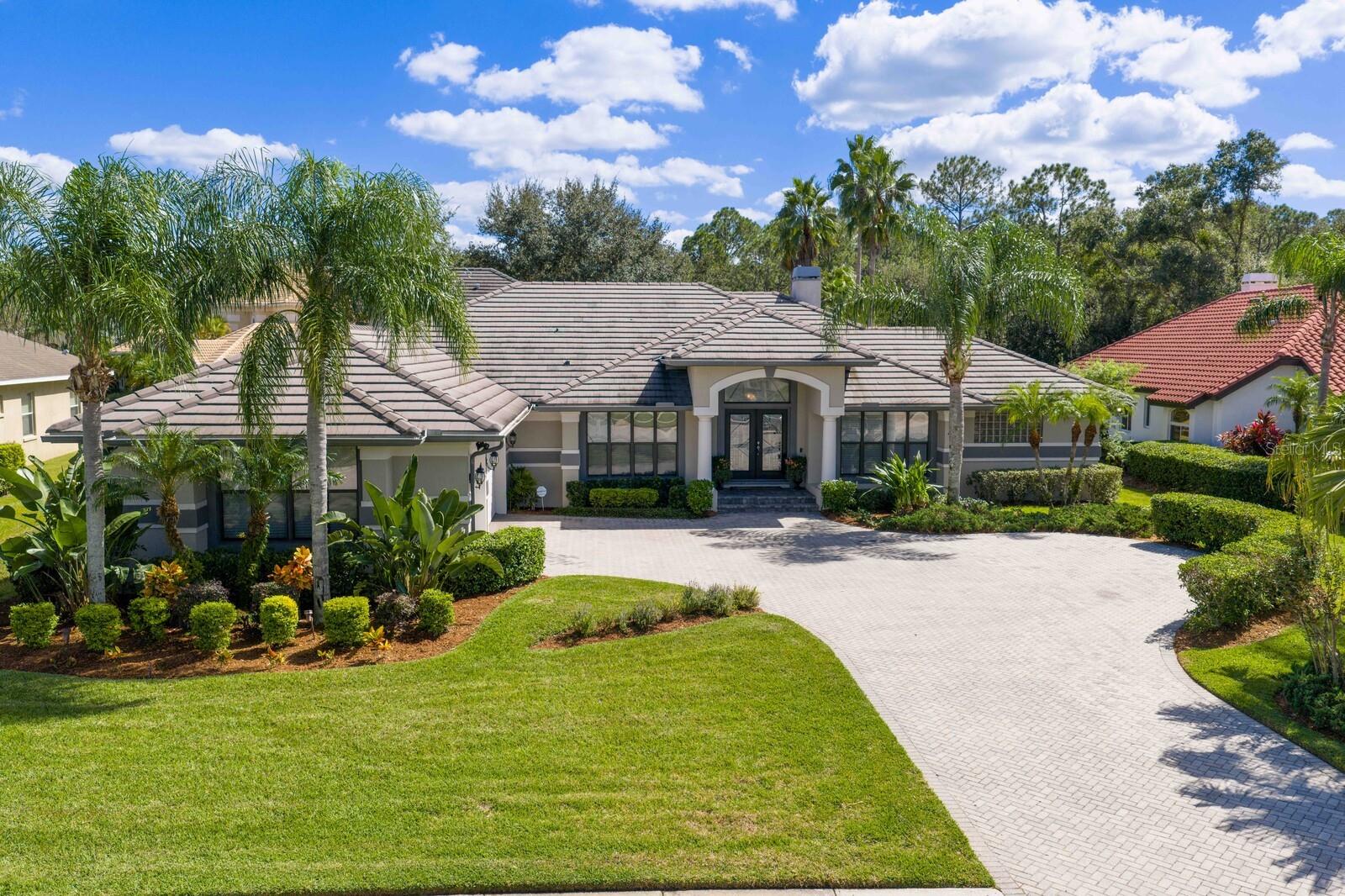 Located in the prestigious manned and guard-gated community of Cory Lake Isles, this northwest-facing, one-of-a-kind custom estate sits on an oversized homesite with private conservation views. From the moment you arrive, the curb appeal is undeniable—an impressive winding pavered driveway leads to a charming courtyard entry and stately double-door foyer. Inside, you’ll find 5 bedrooms, 5 bathrooms, a private office, and a large bonus room, all showcasing custom craftsmanship and rich finishes. The grand foyer sets the tone with soaring scale, column accents, and wood floors that flow through most of the home. The office features plantation shutters, built-ins, and elegant wood flooring, while the formal spaces impress with crown molding, a coffered ceiling, wet bar, built-in hutch, and a wood-burning dual fireplace that is featured in both the living room and primary bedroom. The primary suite is a true retreat with wood floors, and a spa-inspired bath featuring tumbled marble flooring, walk-in closet, detailed tile accents, and custom maple cabinetry. The gourmet kitchen is designed for entertaining with stainless steel appliances, double ovens, maple cabinetry, granite countertops, and an oversized island workstation. The split floor plan ensures privacy, placing the primary suite near the formal areas, two bedrooms near the kitchen and family room, and two more bedrooms toward the rear of the home. The family room highlights wood floors, custom built-ins, and pocket sliding glass doors opening to the outdoor living space. Upstairs, the oversized bonus room offers a full bath and kitchenette with refrigerator, sink, and microwave—perfect as a media room, guest quarters, or in-law suite. The outdoor oasis is extraordinary, with a full outdoor kitchen, large covered lanai, heated spa, cascading waterfall, self cleaning pool, fire pit seating area, and extended pavered patio, all surrounded by lush landscaping. Cory Lake Isles is more than a neighborhood—it’s a lifestyle. Residents enjoy a 165-acre ski lake for boating, fishing, and water sports, along with resort-style amenities including a waterfront beach club, fitness center, playgrounds, parks, tennis and pickleball courts, and a community pool. This rare estate offers luxury living inside and out, with the best of Tampa’s premier gated lakefront community. Welcome Home!