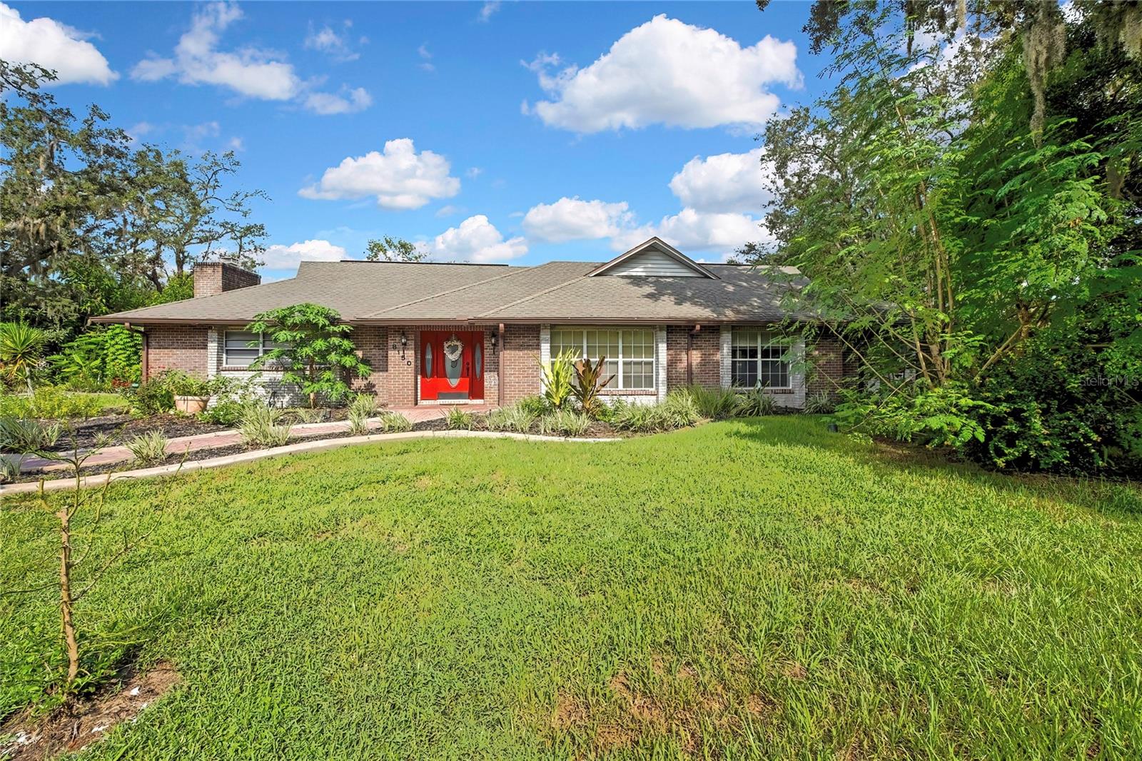 What a unique, one-of-a-kind brick home! This spacious 3-bedroom, 2-bath home with an oversized garage and tons of storage is full of character, space, and special features you simply don't find every day. Step inside to a formal living room and formal dining room, then continue into the huge family room featuring a cozy wood-burning fireplace and French doors leading to the expansive screened lanai. A charming nook area offers the perfect spot for bench seating or a cozy breakfast area. The open kitchen features beautiful marble-look granite countertops, white cabinetry, and plenty of workspace and storage. The large primary suite is a retreat of its own, complete with French doors opening directly to the screened lanai, a walk-in tiled shower, vanity with tiled walls, and walk-in closet. The second and third bedrooms are both nicely sized, and storage is everywhere--including a large hall closet and closets throughout the home. Step outside and you'll quickly see what makes this property so special. The huge screened lanai offers incredible privacy and overlooks a beautifully landscaped backyard filled with established gardens and an amazing variety of fruit-bearing plants and trees, including lemongrass, avocado, Brazilian cherries, papayas, guava, plantains, white yuka, dragon fruit, pomelos, sweet lemons, oranges, blackberries, pineapples, guava, and a moringa tree. A brick walkway welcomes you to the front door, while the beautifully landscaped property features a long driveway leading to the garage and additional storage area that is already plumbed for a bathroom, offering even more possibilities. A separate laundry room is conveniently located between the lanai and garage. The backyard also features a white vinyl privacy fence, large storage shed, and plenty of room to enjoy the Florida lifestyle. With its incredible amount of living space, storage, privacy, gardens, outdoor living areas, and unique character, this truly is a one-of-a-kind home you don't want to miss!