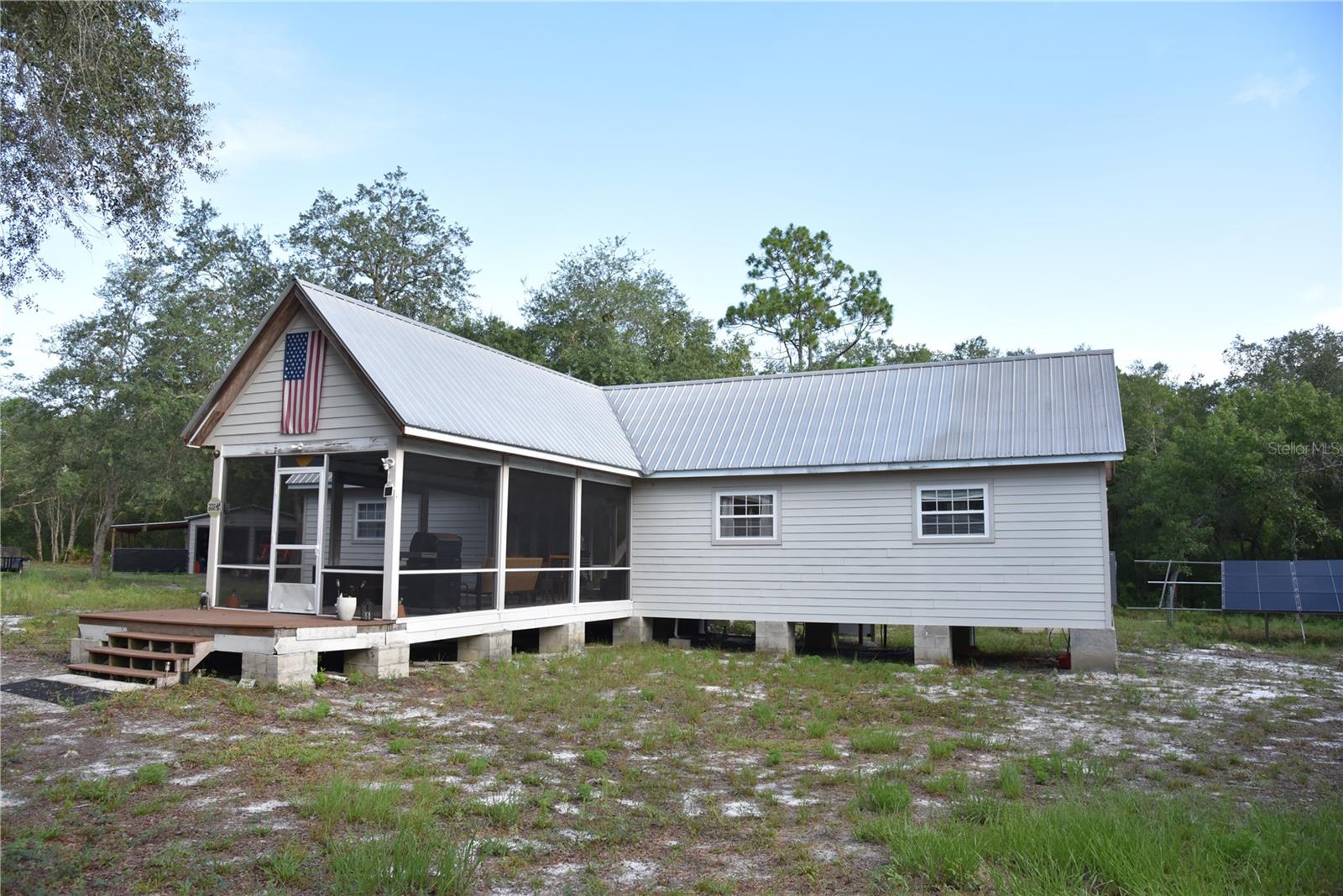 Escape to a fully outfitted hunting camp bordering state land, offering privacy, easy access, and game management already done for you. Tucked in North Central Florida within reach of Palatka, Gainesville, Jacksonville, and St. Augustine, this property blends true off-grid convenience with serious hunting infrastructure, making it just as suited to a weekend retreat as to a dedicated hunting operation. The camp is anchored by a small 2-bedroom, 1.5-bathroom lodge alongside a separate metal building, both powered by the property's solar array, giving you comfortable, self-sufficient shelter for overnight stays plus dedicated storage and workspace without dependence on the grid. The solar power keeps lights, appliances, and gear charged and ready between trips, so arriving at camp feels no different than flipping a switch at home. A gated entrance provides controlled access and privacy, keeping the property secure when no one is on site, while an established network of interior roads reaches every corner of the property by truck or ATV. That road system means checking stands, refilling feeders, hauling out game, or moving equipment around camp is simple rather than a battle with the terrain. Hunters will appreciate the work that has already gone into this property. Multiple cleared food plots throughout, each paired with box stands positioned over the openings to take advantage of natural travel corridors. Feeders are already in place and running, so there is no scramble to set up before the season starts. A small seasonal creek also runs through the property, adding another natural water source that draws wildlife through the cleared areas and stands. The land has been strictly managed, meaning the game populations here reflect real, ongoing stewardship rather than incidental pressure. Deer, turkey, and hogs are all present in strong numbers, giving hunters a genuine variety of pursuits across the calendar, from spring turkey season through fall and winter deer and hog activity. Bordering state land along the entire north side is a rare and valuable feature, extending the property's usable habitat and travel corridors well beyond its own boundary while helping buffer the land from future development and preserve its character for years to come. The location adds real convenience to the package as well. Sitting close to Palatka and within a manageable drive of Gainesville, Jacksonville, and St. Augustine, the camp is easy to reach for weekend trips while still feeling private and secluded once you are through the gate. Supply runs, fuel, and equipment are never far away, but the camp itself stays quiet, gated, and undisturbed between visits. Whether the goal is a turnkey camp ready to hunt this season without lifting a finger, a private outdoor retreat for weekends away, or a well-managed tract to build on for the long term, this property delivers infrastructure, access, and game numbers that are hard to find already in place. Camps with this level of readiness, this location, and this kind of public-land border do not come along often.