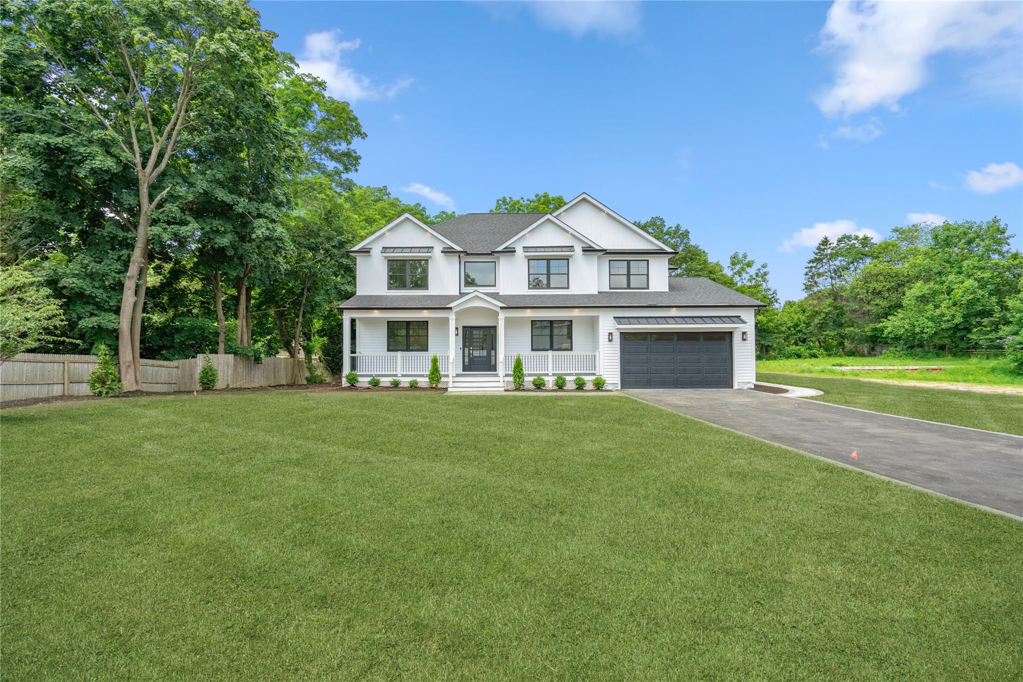 “Hamptons Modern Farm House” in Commack | Where Transitional Elegance Meets Contemporary Luxury… set on 1/2 acre  perfectly flat and manicured. This custom-built house is a unique blend of architectural excellence and modern sophistication. Constructed with white vinyl cedar impressions with Azek board & batten & cultured stone exterior with a combination of metal roofing details that add amazing design & curb appeal. This five bedroom 4 bath offers luxury living at its finest! Inside, dramatic design moments unfold—beginning from the entry porch with a custom white oak staircase with metal balusters that cascades from the upper level to the lower level. Wide-plank white oak floors throughout, extensive millwork, and imported tile and stone throughout set a tone of refined luxury. The chef’s kitchen is the heart of the home which sowcases a custom two-tone off white and mocha cabinetry anchored by a massive mocha finished center island with custom Quartz counters & custom under-lit lighting | high-end Thermador appliances w/ designer fixtures | seamlessly connected to an oversized family room with gas fireplace and French doors leading outdoors. A formal dining room with custom designed coffered ceiling, and up lighting creates an elegant setting for entertaining, the living room is detailed with a custom paneled tray ceiling with up lighting that you can change color to set mood. Guest suite & bath  is located privately on first floor. Second floor leads to large primary suite with custom  acccent wall, tray ceiling with up lighting and color change feature w/ walk-in closet with custom closet kit. Primary bath features custom tile, over-sized shower and soaking tub, double custom oak vanity & radiant heated floors. Three additional bedrooms feature vaulted ceilings with two bedrooms sharing a large pass through bathroom and one additional hall bathroom, Over-sized laundry room w/ washer & gas dryer with custom tile, cabinetry w/ ironing & folding station. Two Car garage with epoxy floors and electric in place to wire any EV. Full un-finished basement with 9’ ceilings to finish w/ outside entry to yard. Lower-level awaits your design plan to make your very own! Rear yard features a paver patio off French doors offering plenty of space to design our outside oasis! Front yard professionally landscaped with beautiful new sod & plantings awa well as sprinkler system. Mechanicals are state-of-the-art & energy efficient. MUST SEE!