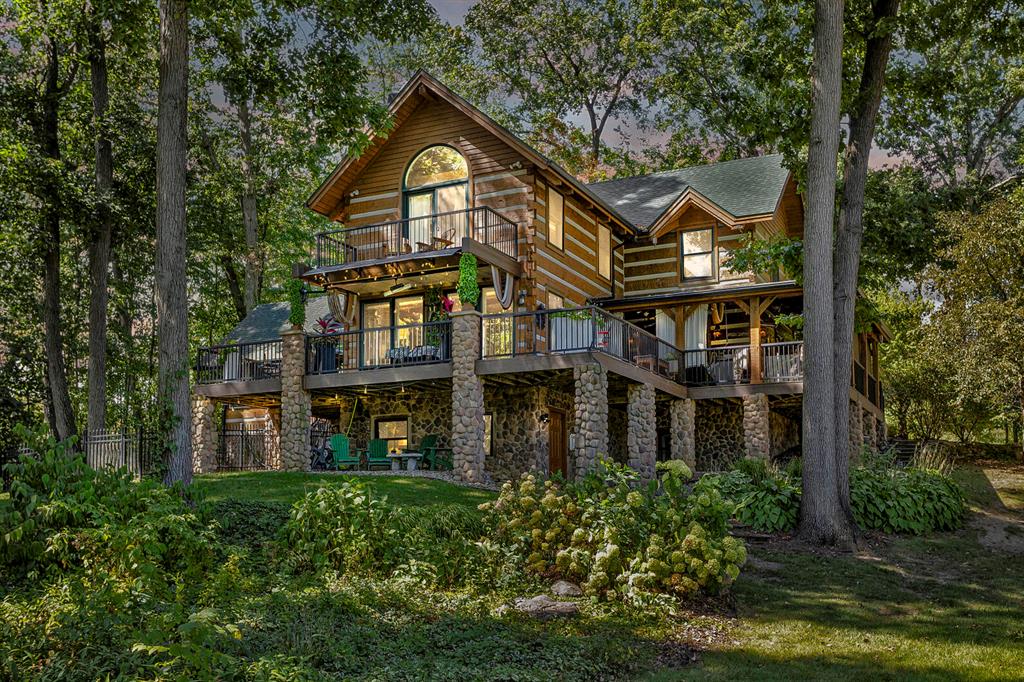 A RARE LAKEFRONT JEWEL OF SECLUDED LUXURY! Tucked deep within a canopy of mature woods and set across 2+ pristine scenic acres, this exceptional log estate offers an unmatched level of privacy, prestige & natural beauty. With 165 feet of private frontage, sweeping views and your own personal sandy beach along Southern Michigan's most desired chain of crystal-clear-Caribbean-blue lakes exploring through Rainbow, Farwell, Pinehill & Fox lakes, this is a sanctuary where time slows and elegance reigns. Every detail of this home is crafted with impeccable attention to detail, the residence showcases masterfully hewn log architecture, soaring cathedral ceilings and refined interior finishes that balance rustic sophistication with upscale comfort. Expansive living spaces flow seamlessly into a grand screened-in veranda, providing a three-season sanctuary for dining, entertaining or quiet reflection of tranquil lakeside living. Cozy up this Fall to the warmth of the natural stone fireplacethat anchors the great room. The stonework continues outside, with matching stone pillars flanking the entry and elevating the home's presence. Enjoy entertaining in the chef's kitchen, equipped with sleek new appliances & center island for gatherings. The second-level primary suite offers a true private retreat, complete with a lakeside balcony, dual vanities, clawfoot tub & separate shower plus a lengthy walk-in closet. The other three bedrooms on the second floor are spacious while featuring robust timber beam ceiling architecture. Immerse yourself in the finished walkout lower level where it expands the home's livable space and versatility for guest accommodations, multi-generational living, or work-from-home options. With natural daylight, a fifth bedroom, additional living room area and a flexible space ideal for a sixth bedroom, home office, gym, or studio plus it's already plumbed for a future bathroom, this space offers it all. Some of the recent updates include new furnace, house roof, gutters with gutter guards, stone retaini